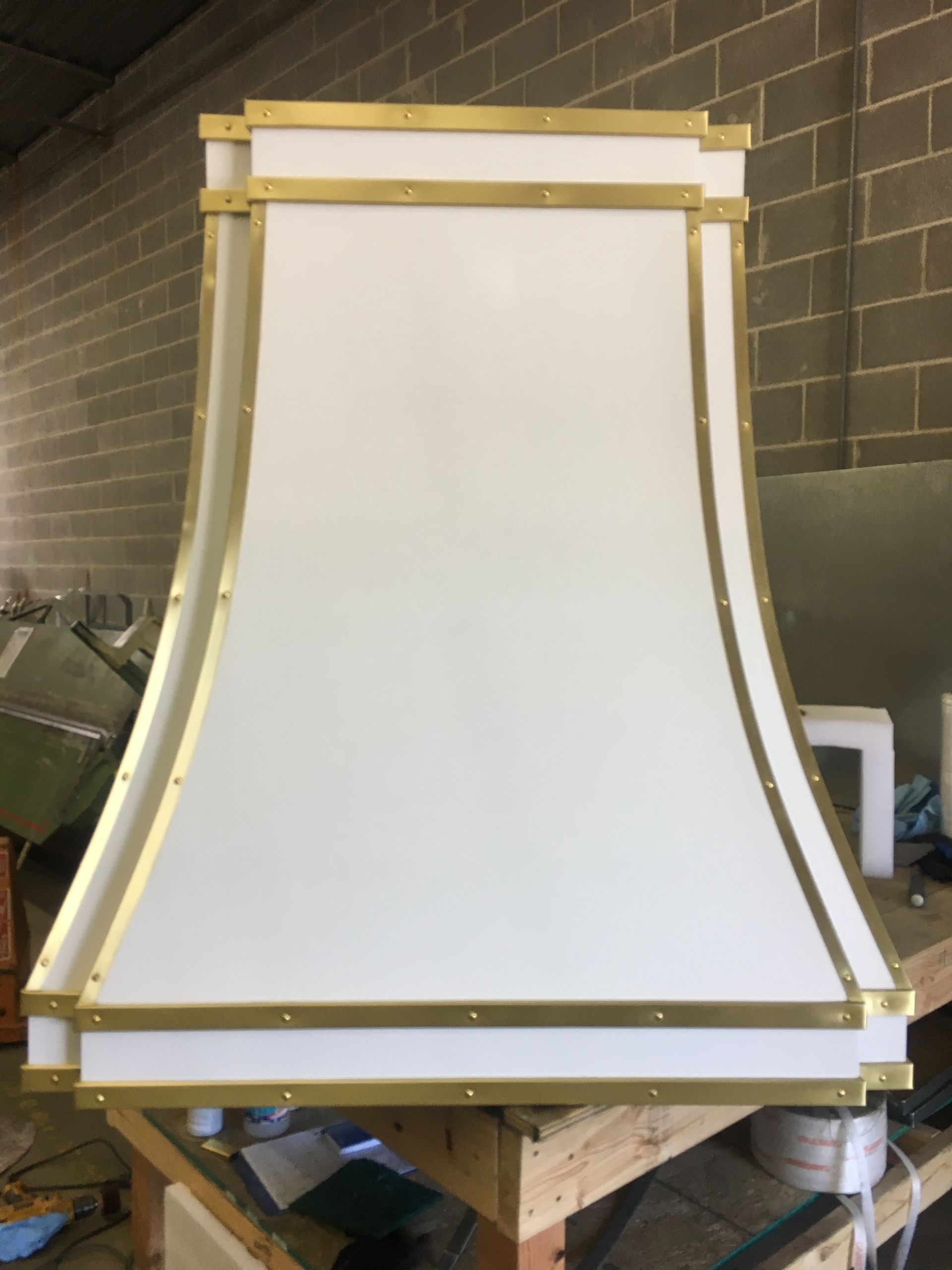 A white hood with gold trim is sitting on a wooden table.