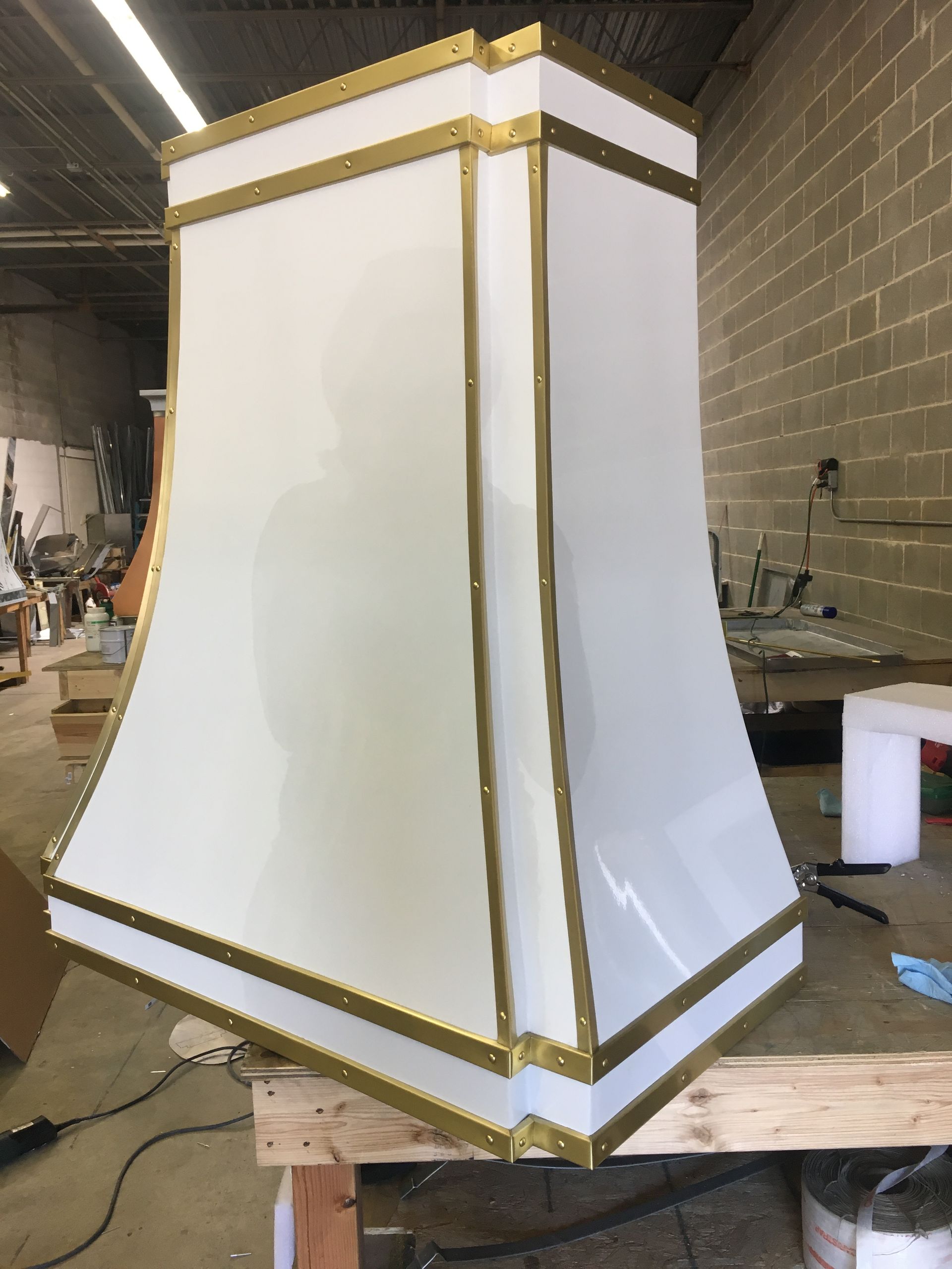 A white lamp shade with gold trim is sitting on a wooden table.