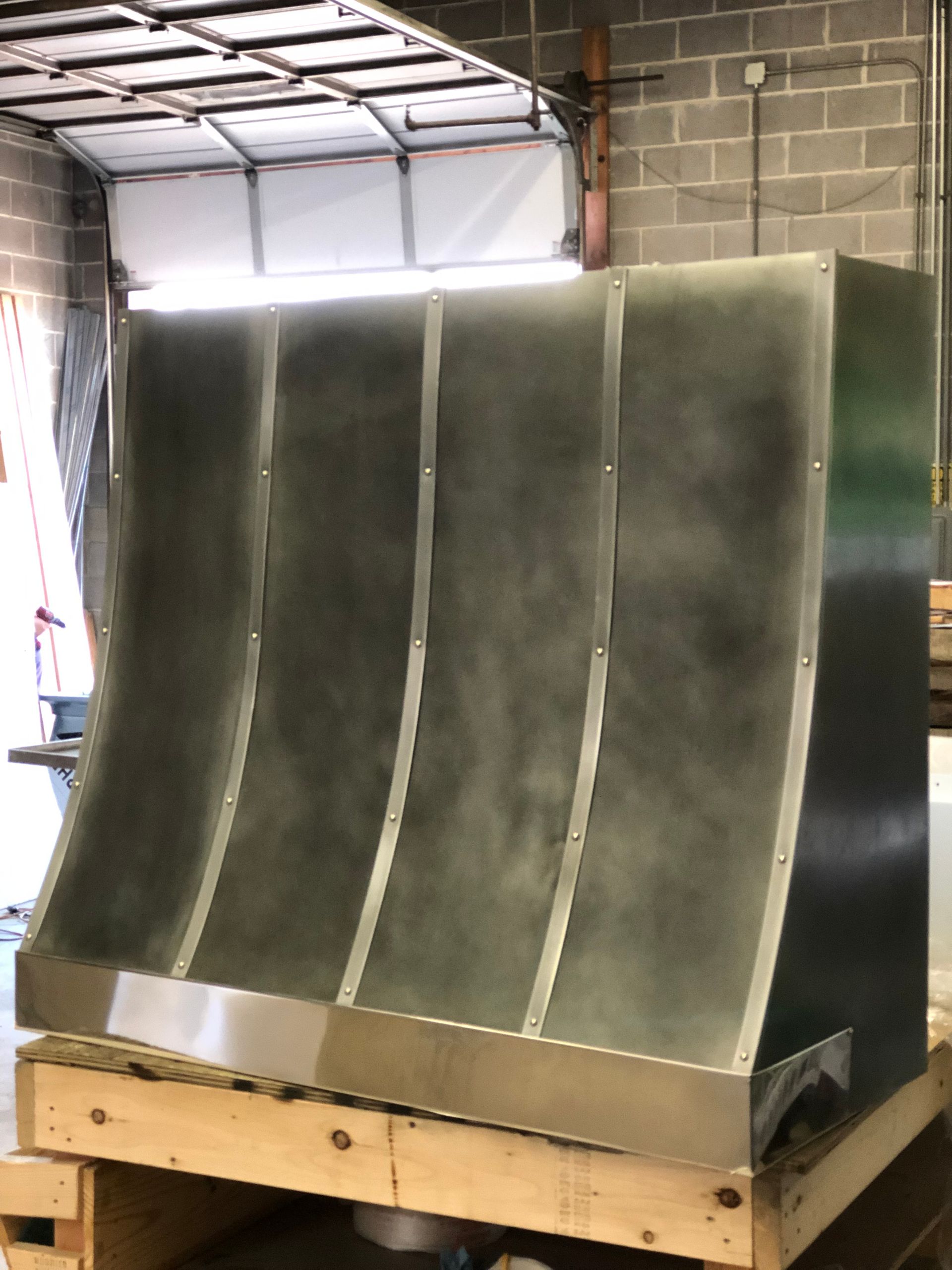 A stainless steel hood is sitting on top of a wooden pallet.
