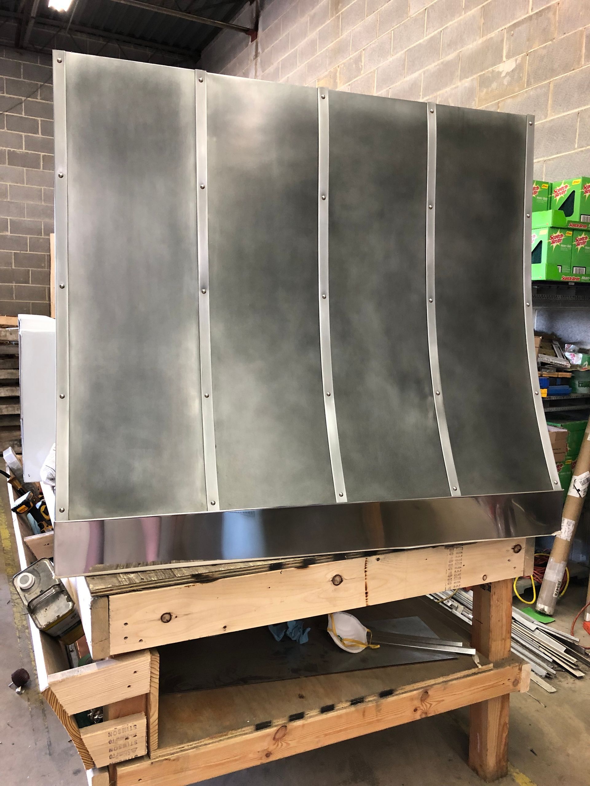 A stainless steel hood is sitting on top of a wooden table