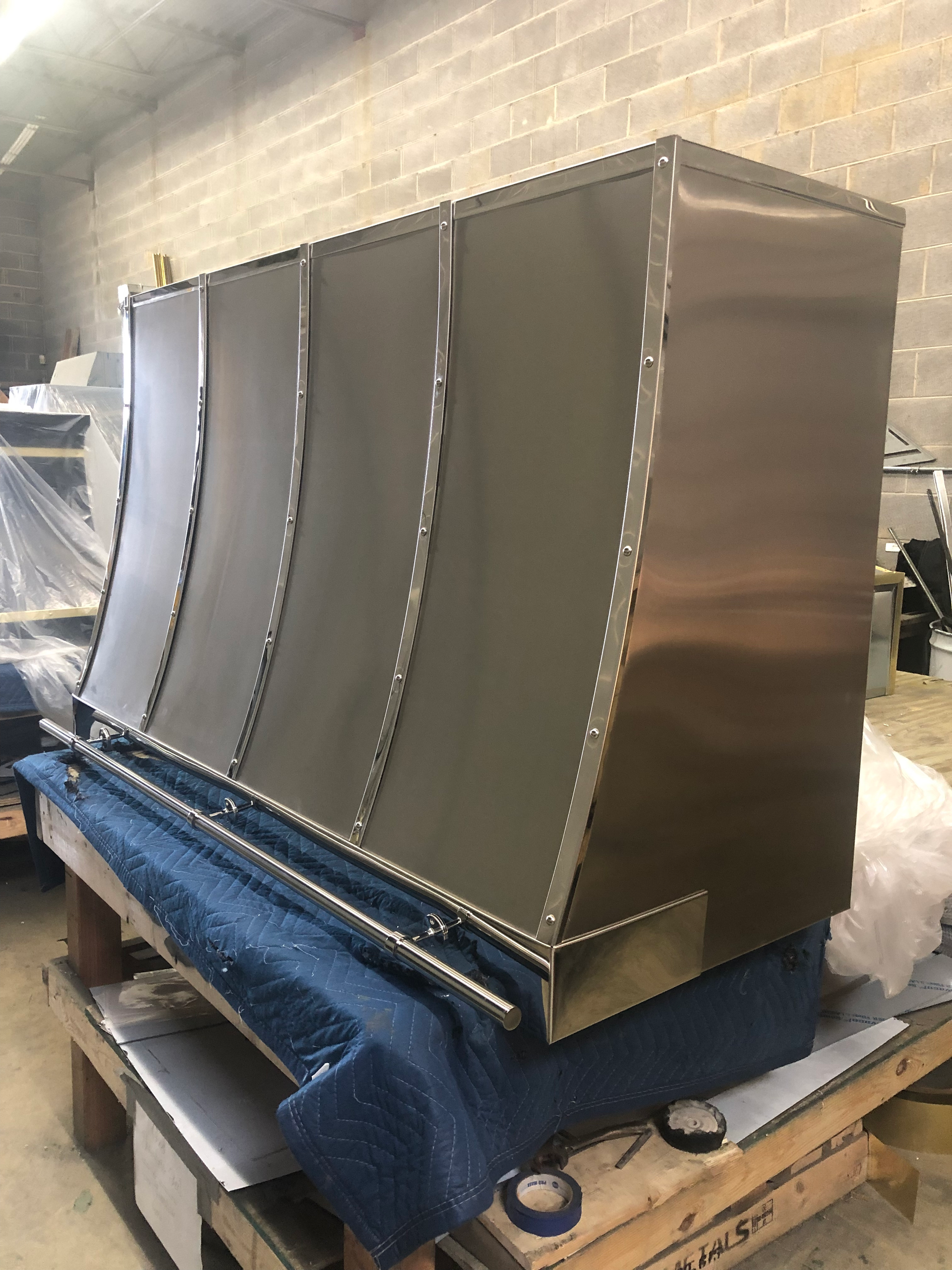 A stainless steel hood is sitting on top of a wooden table.