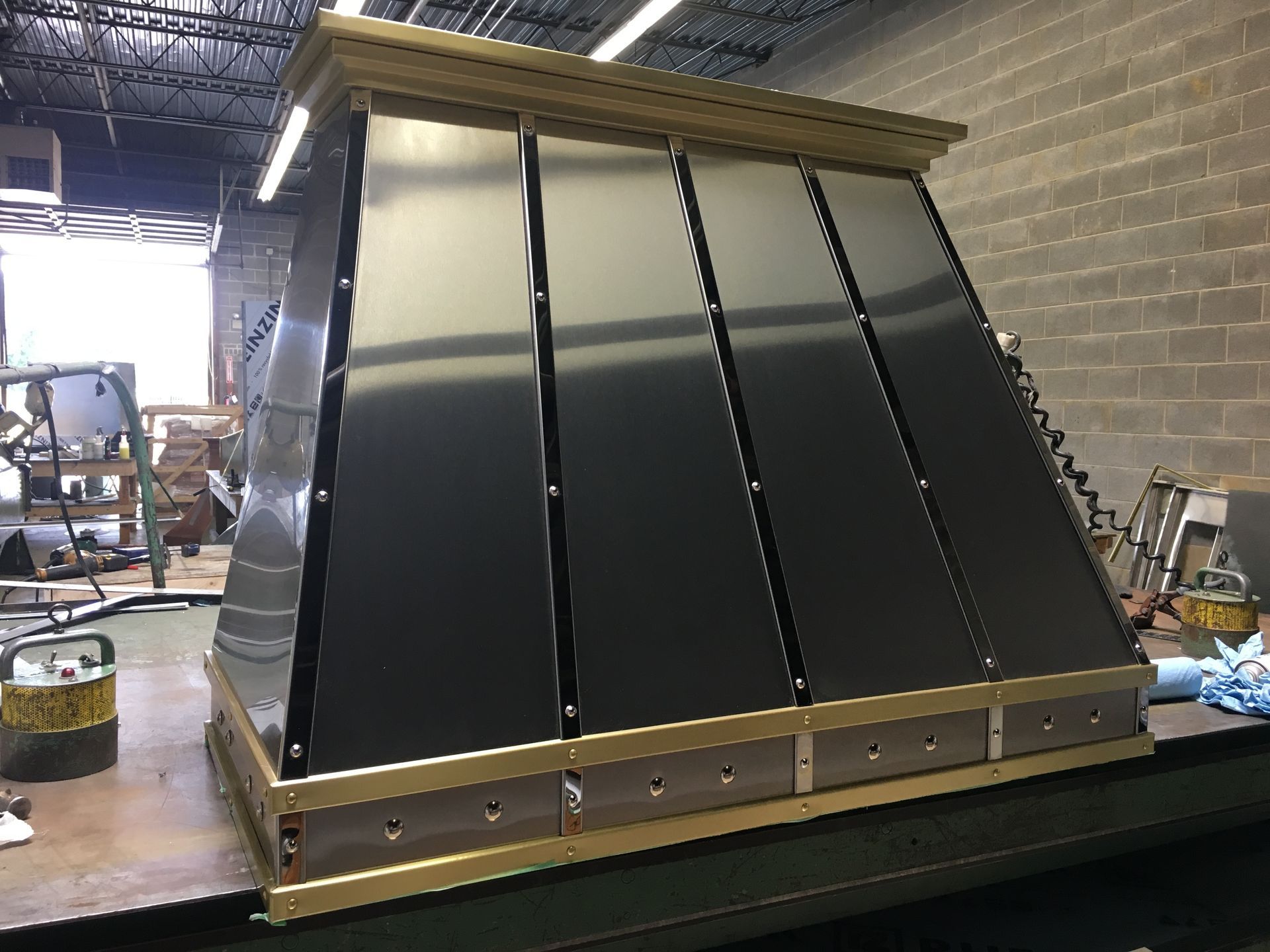 A stainless steel hood is sitting on top of a wooden table.