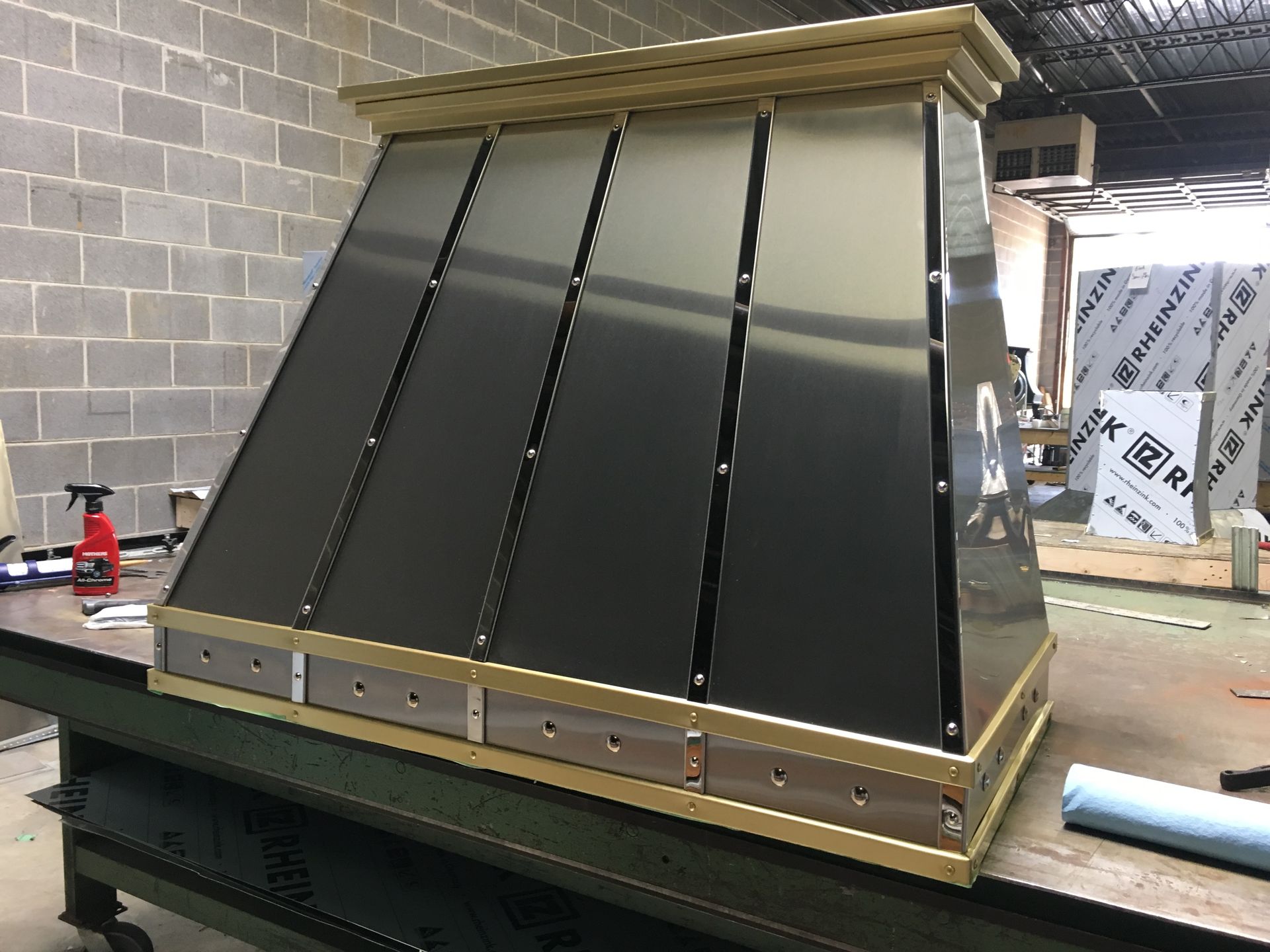 A stainless steel hood is sitting on top of a wooden table.