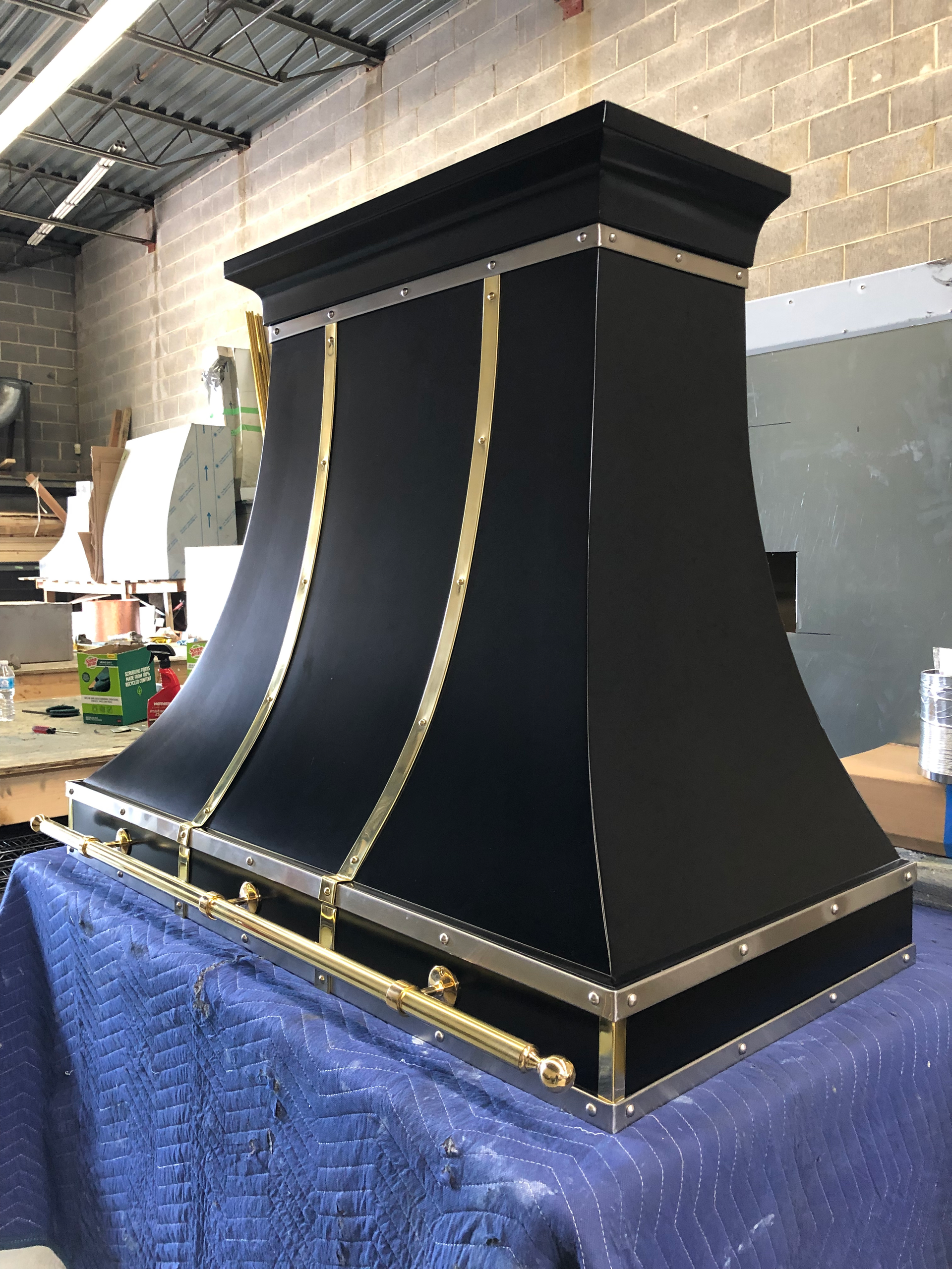 A black and gold hood is sitting on top of a blue table.