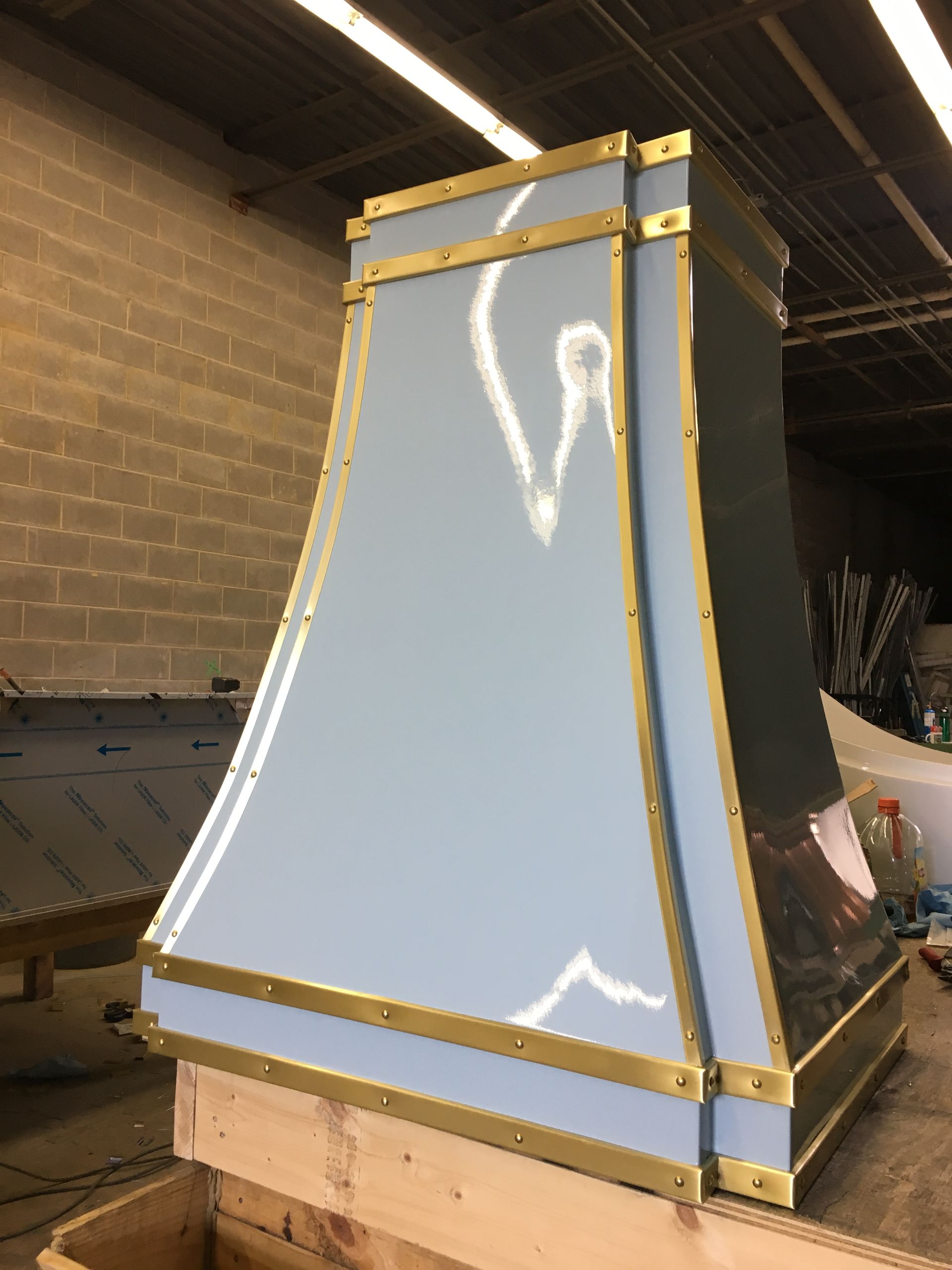 A stainless steel hood with brass trim is sitting on top of a wooden box.