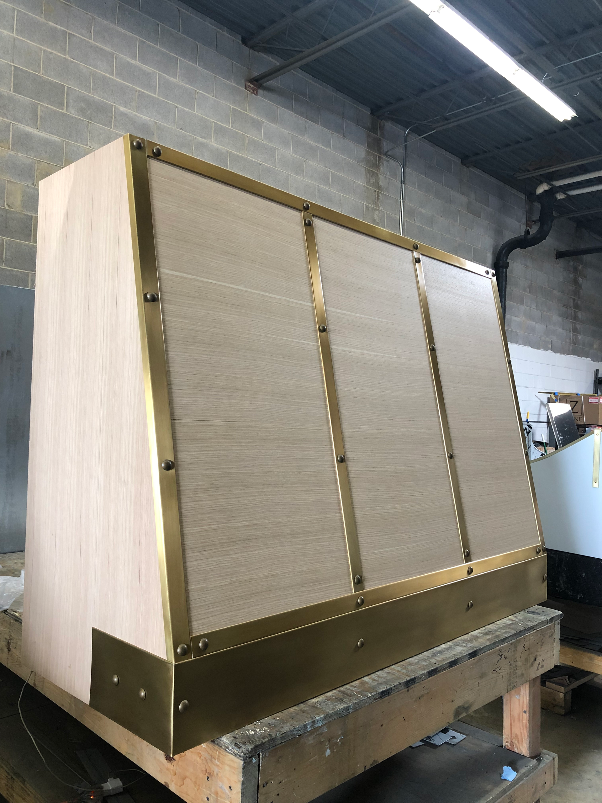 A wooden cabinet with brass trim is sitting on top of a wooden table.