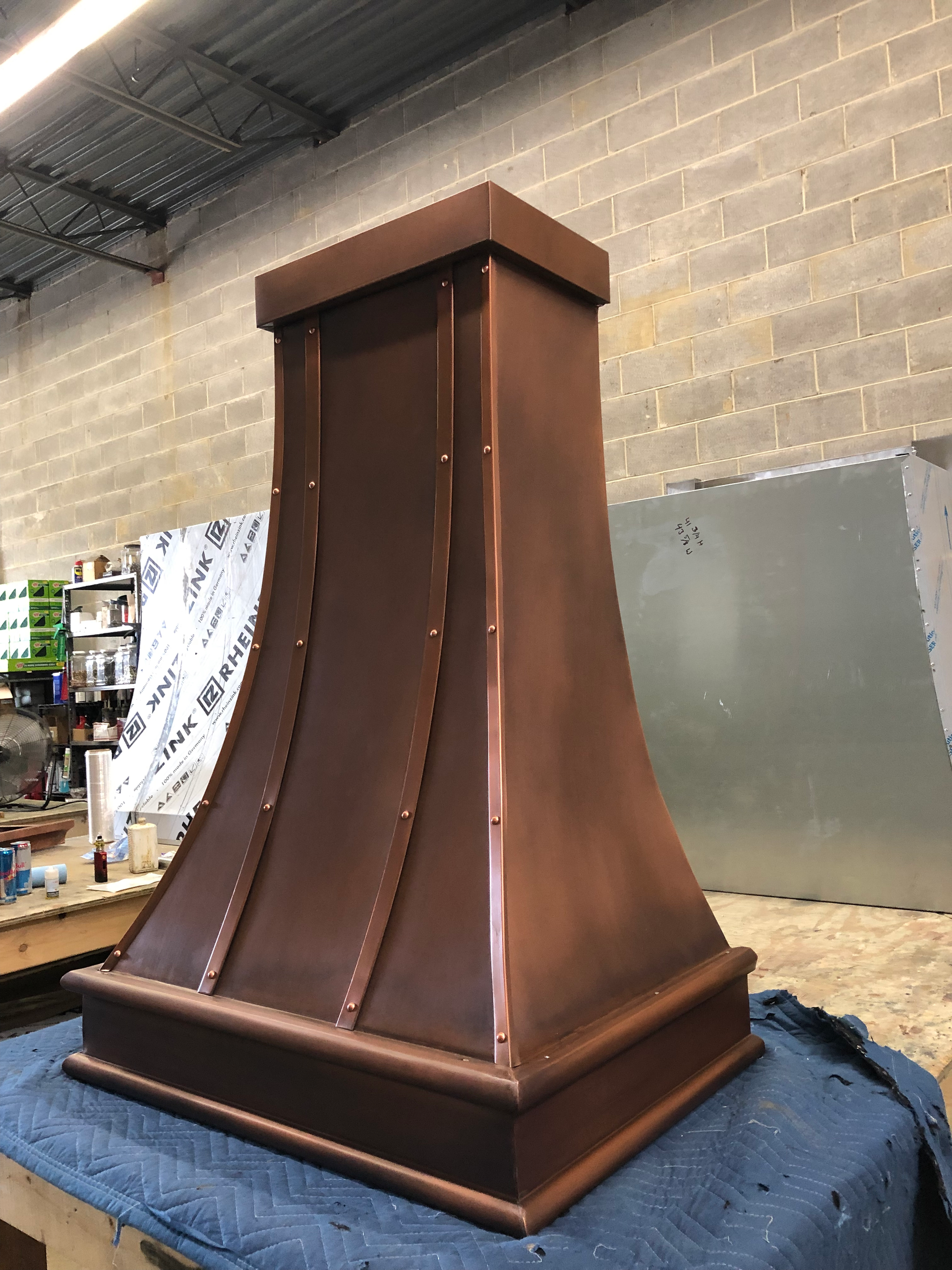 A copper hood is sitting on a table in a room