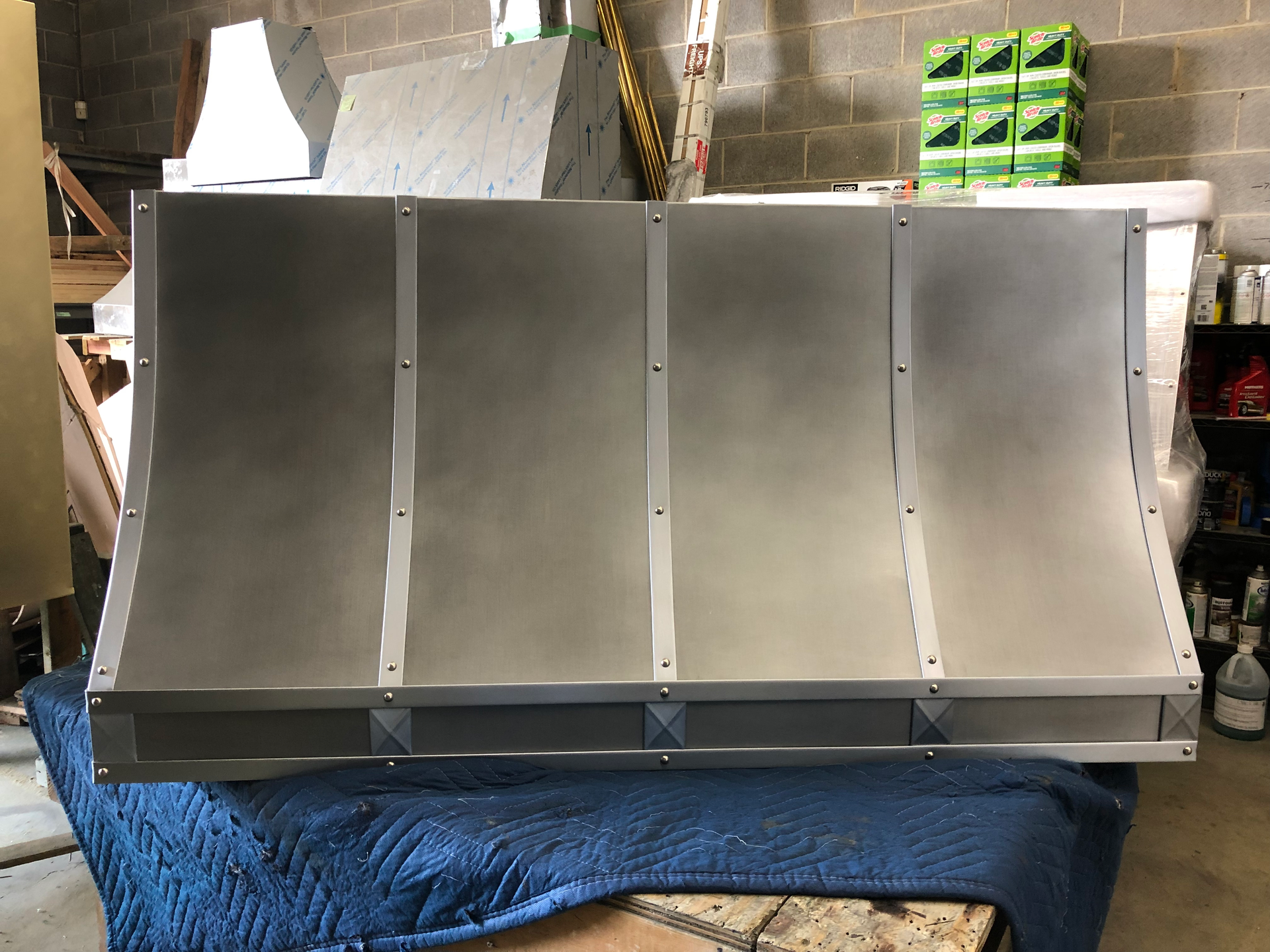 A large stainless steel hood is sitting on top of a blue blanket.