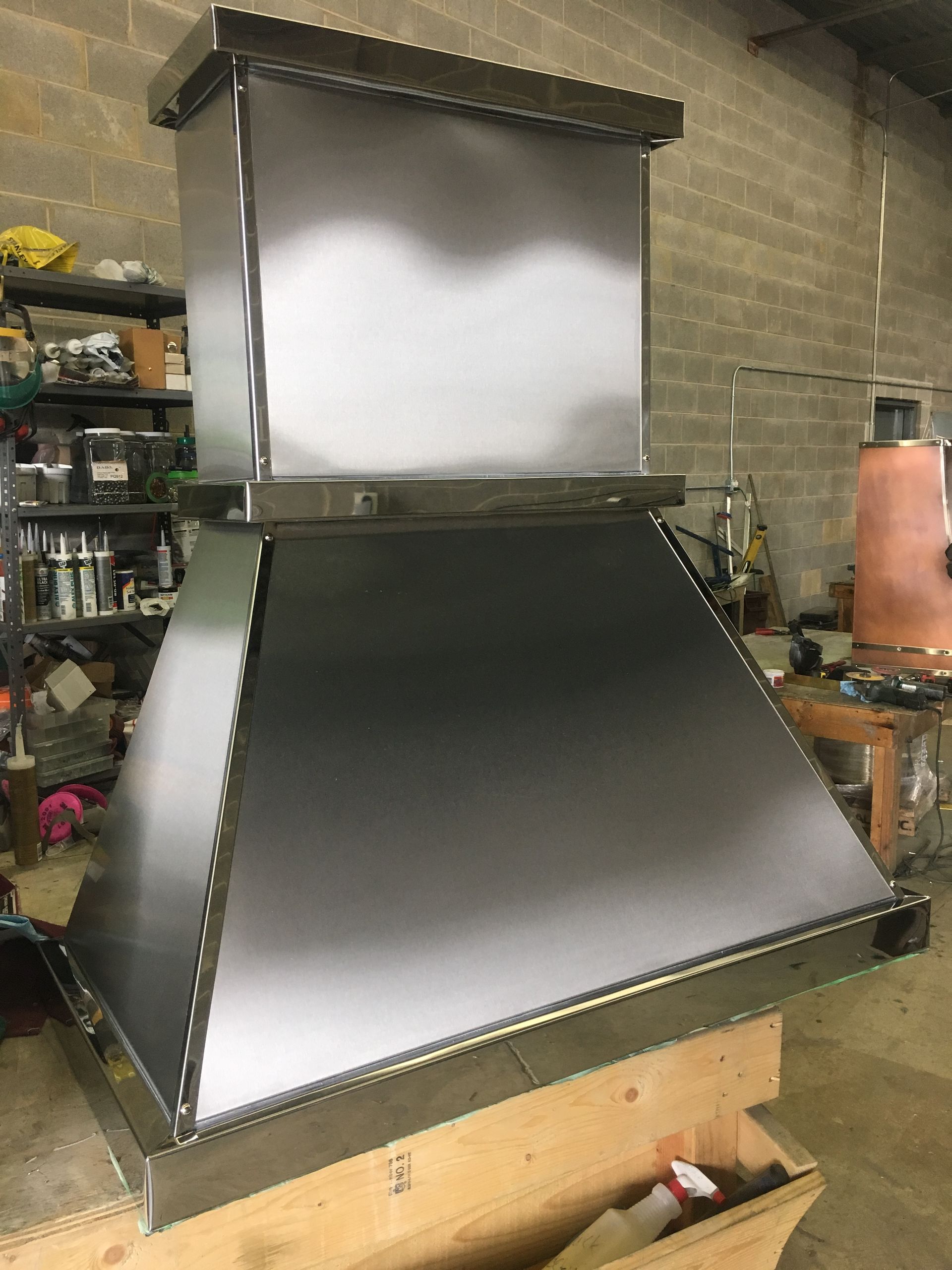 A stainless steel hood is sitting on top of a wooden table in a room.