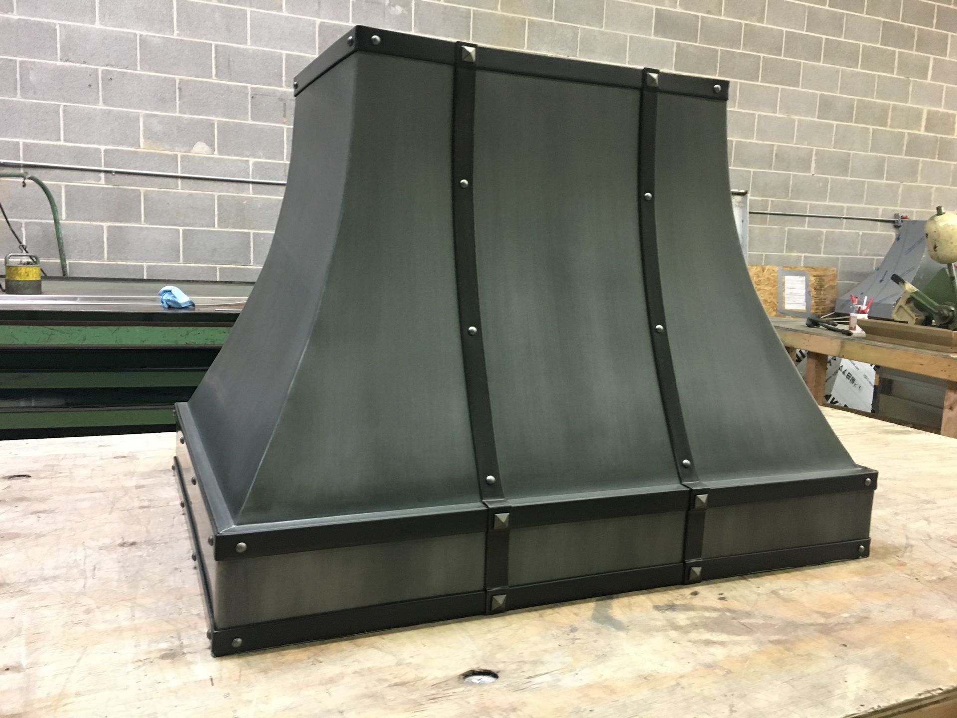 A metal hood is sitting on top of a wooden table.