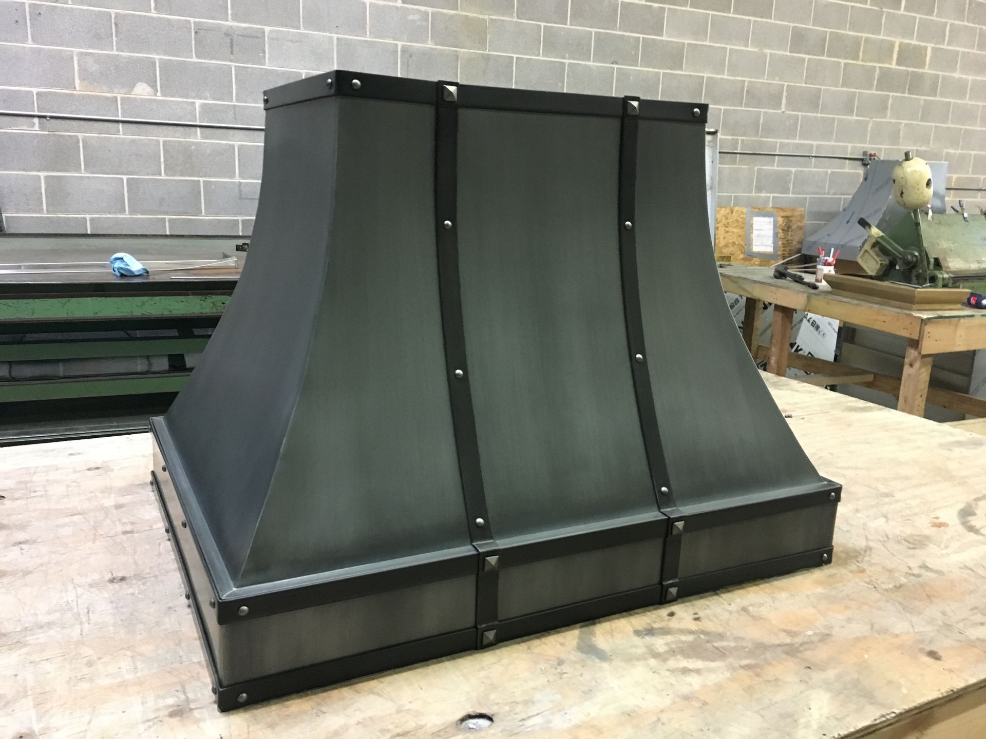 A black metal hood is sitting on top of a wooden table.