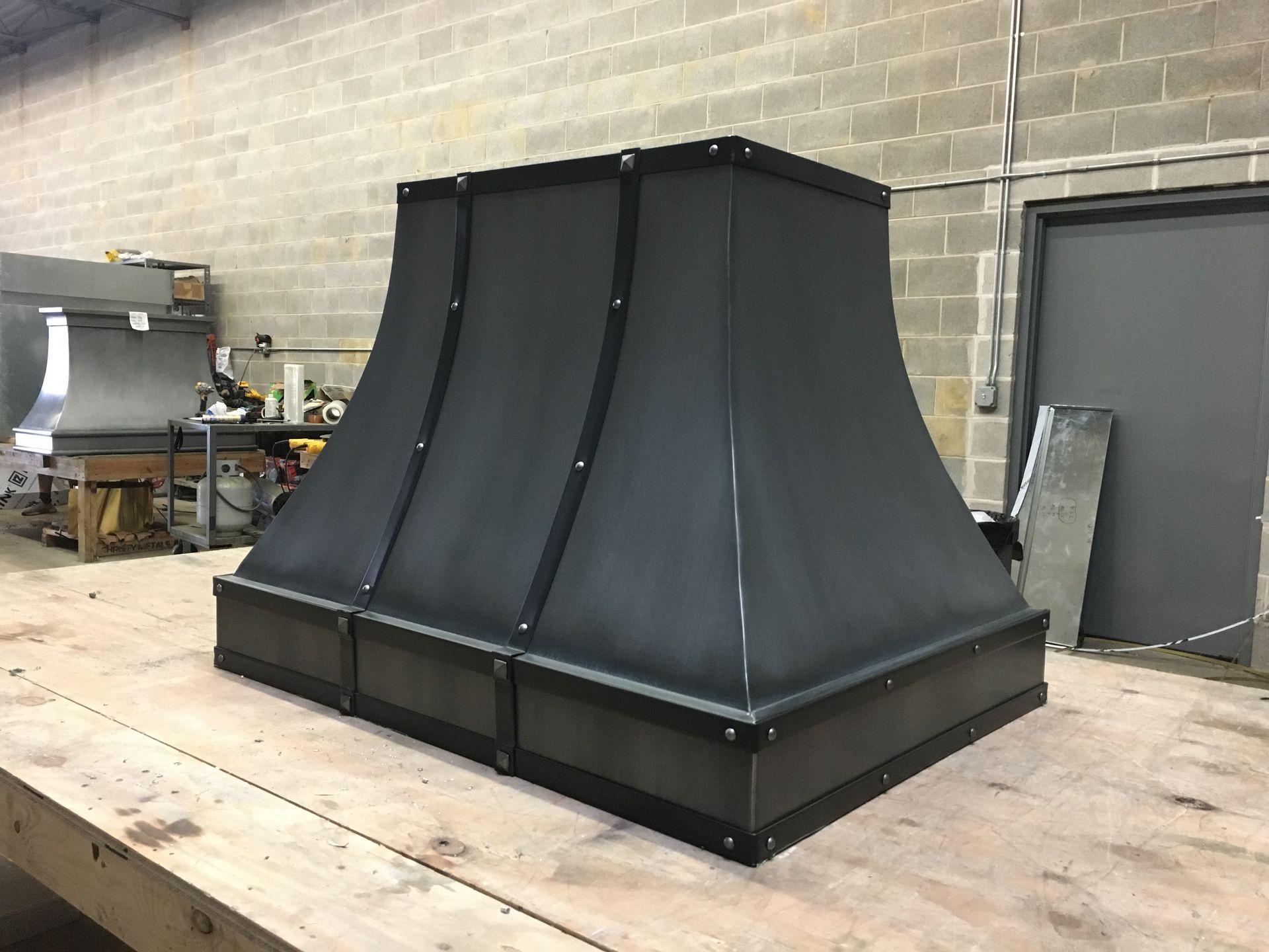 A black chimney hood is sitting on top of a wooden table.