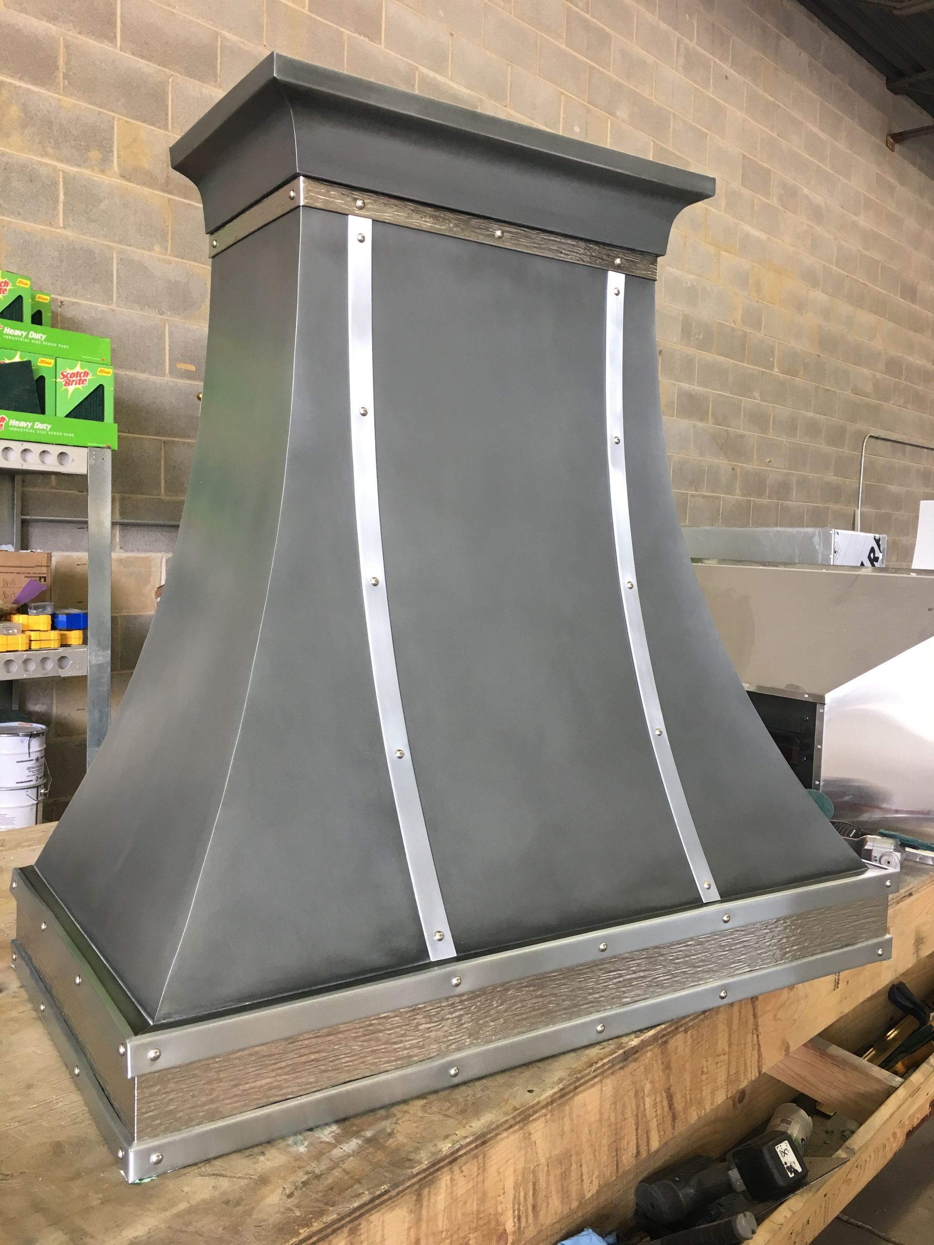 A metal hood is sitting on top of a wooden table.