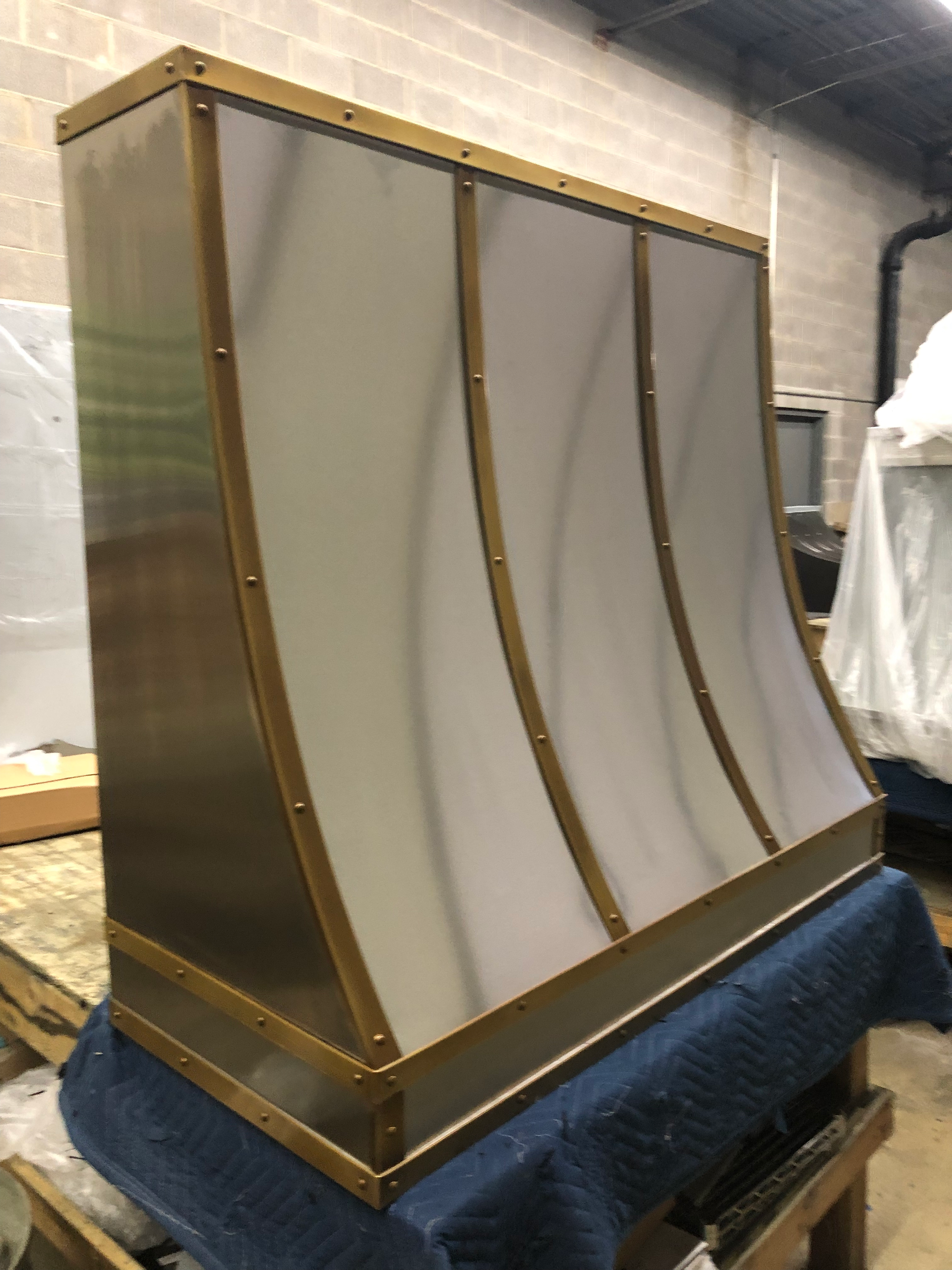 A stainless steel hood is sitting on top of a blue table.