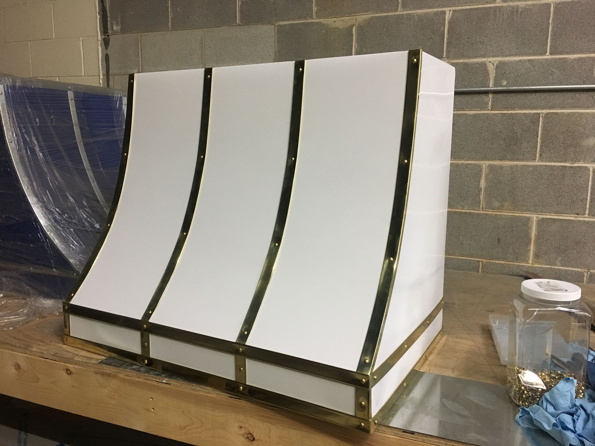 A white box with brass trim is sitting on a wooden table.