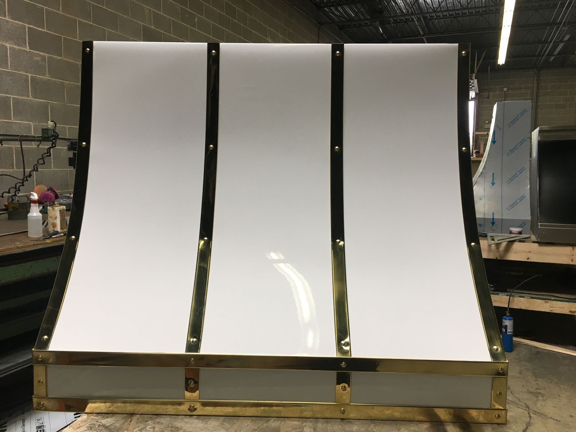 A stainless steel hood with brass trim is sitting on a wooden table.