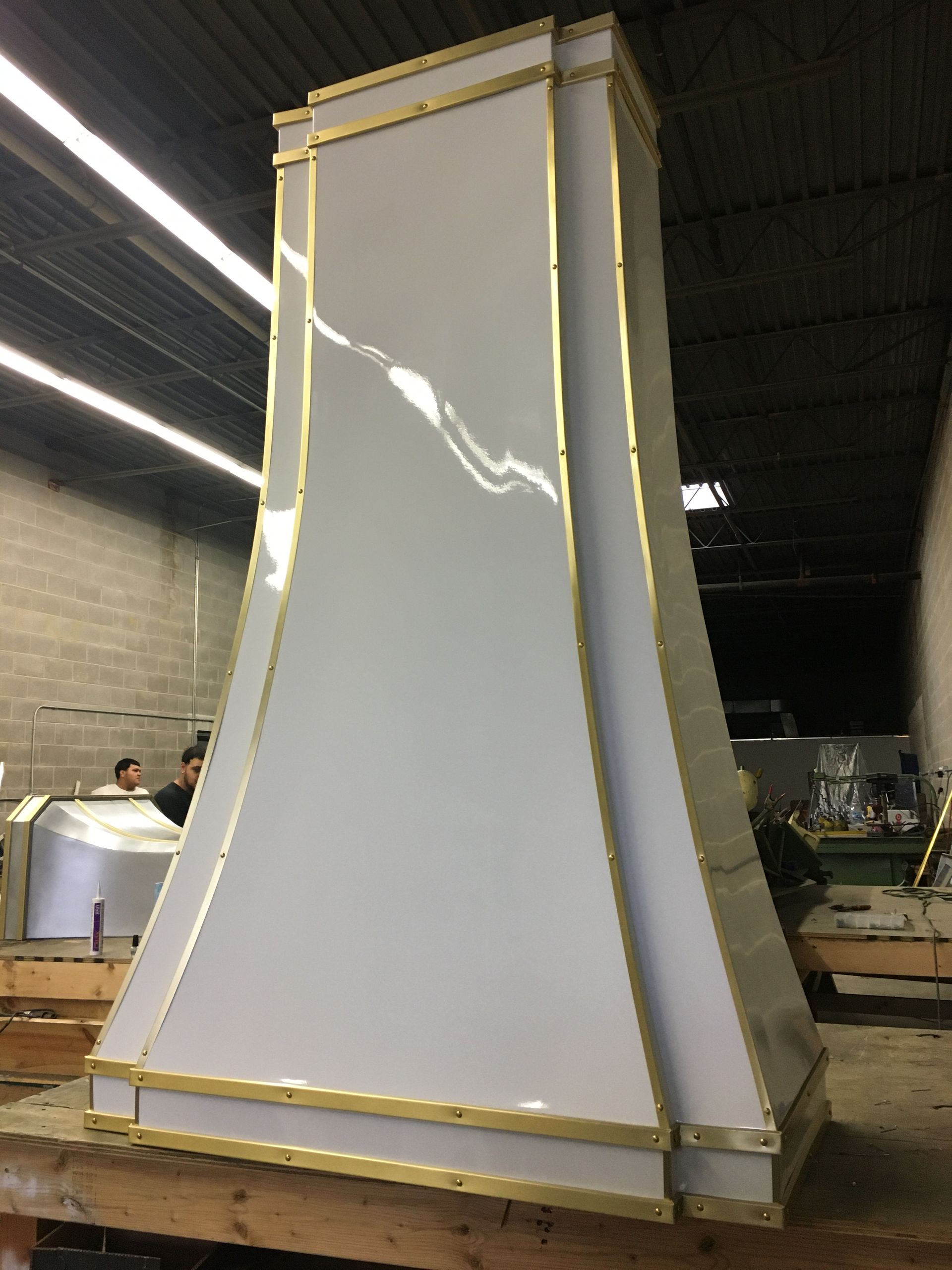 A white chimney with gold trim is sitting on a wooden table.