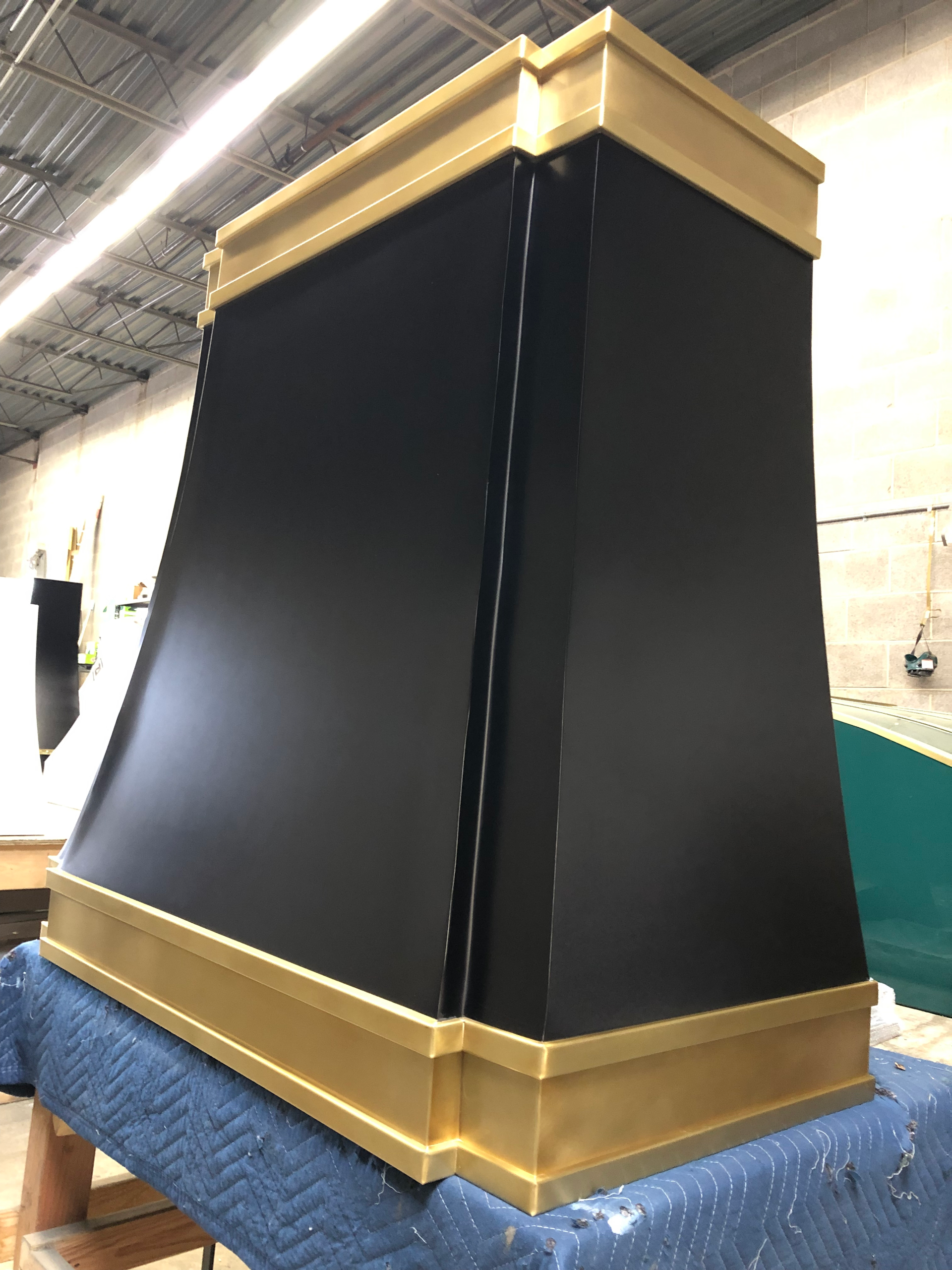 A black and gold hood is sitting on top of a blue table.
