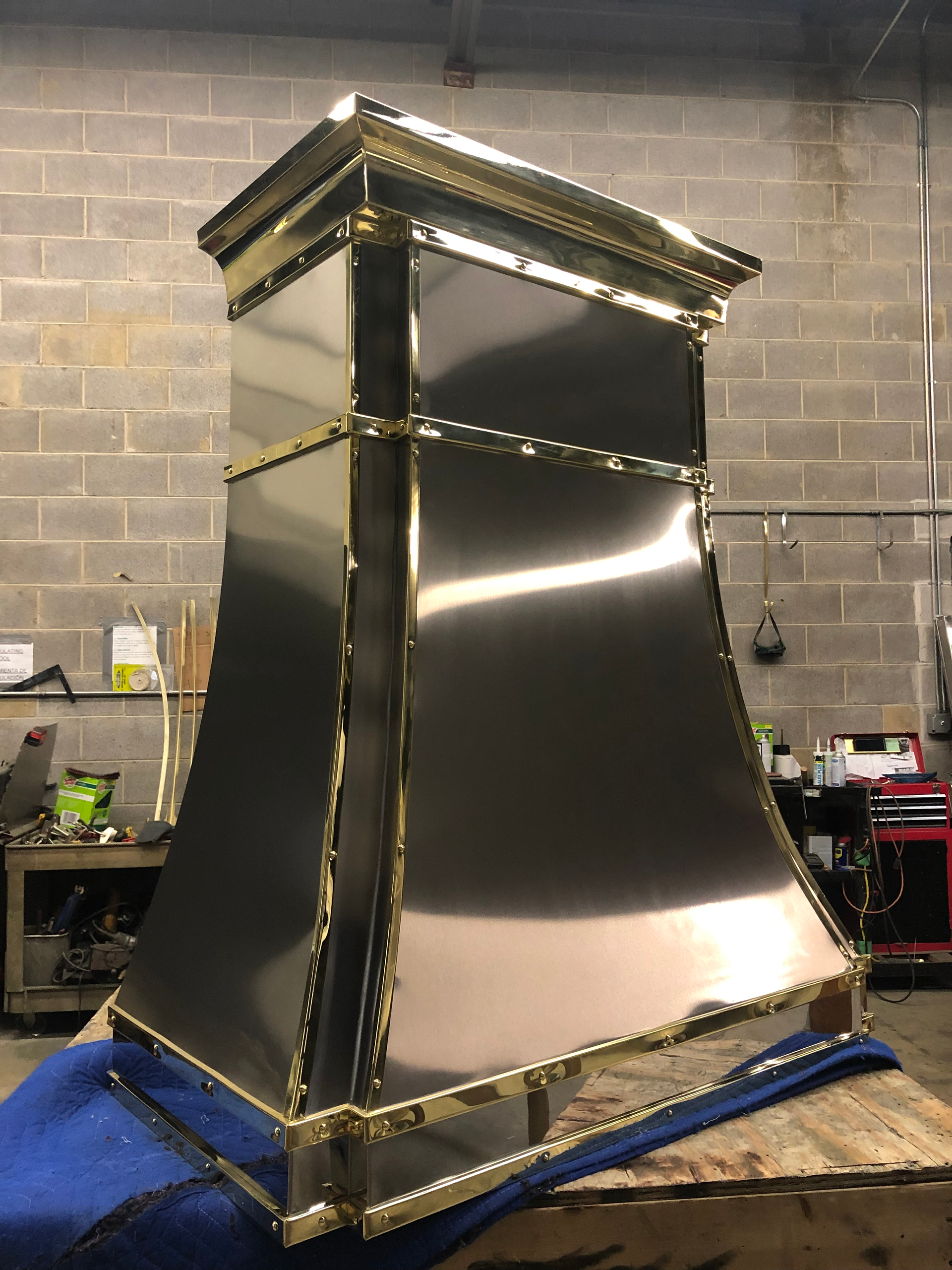 A stainless steel chimney hood is sitting on top of a wooden table.