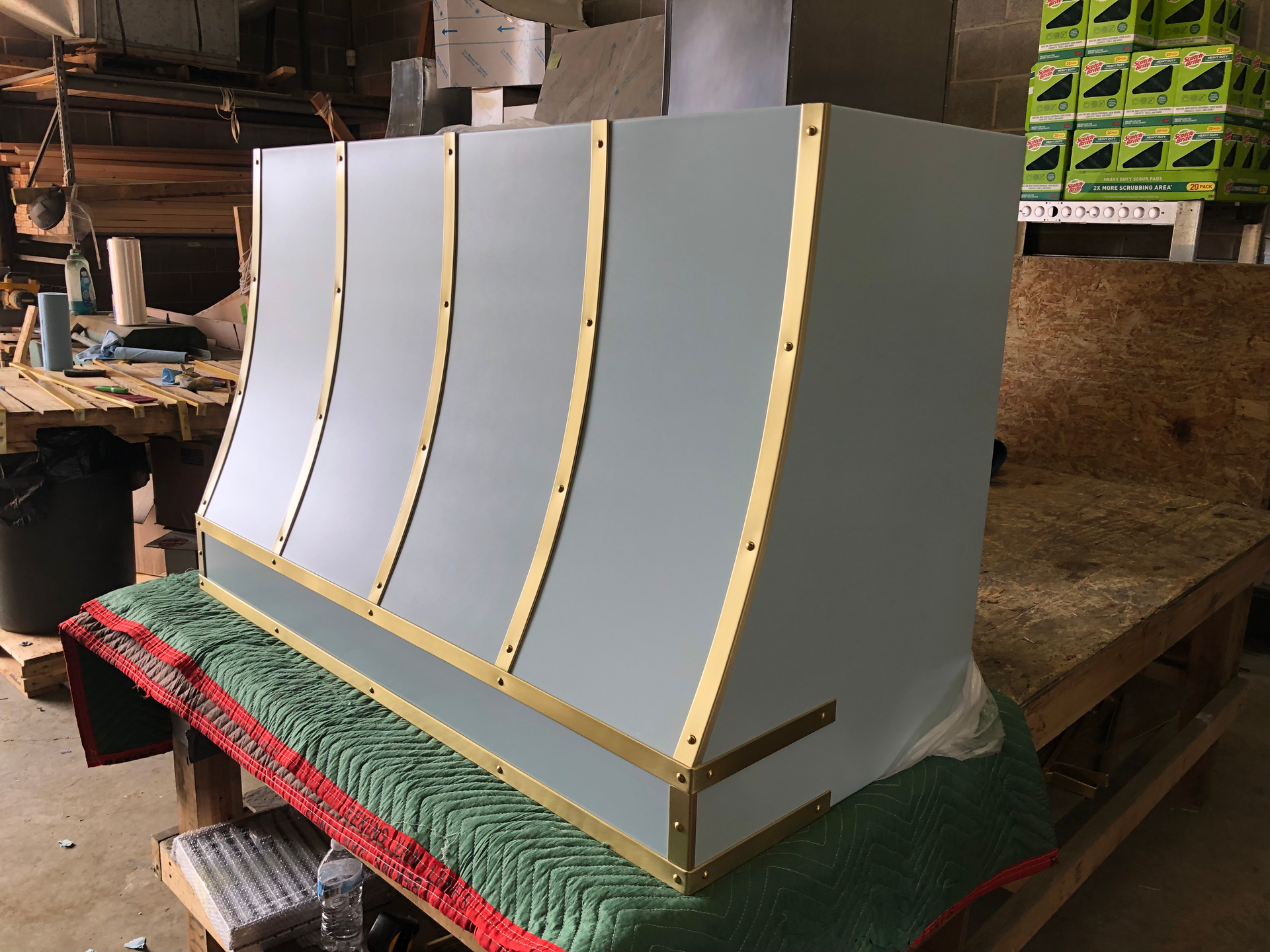 A kitchen hood is sitting on a green blanket on top of a wooden table.