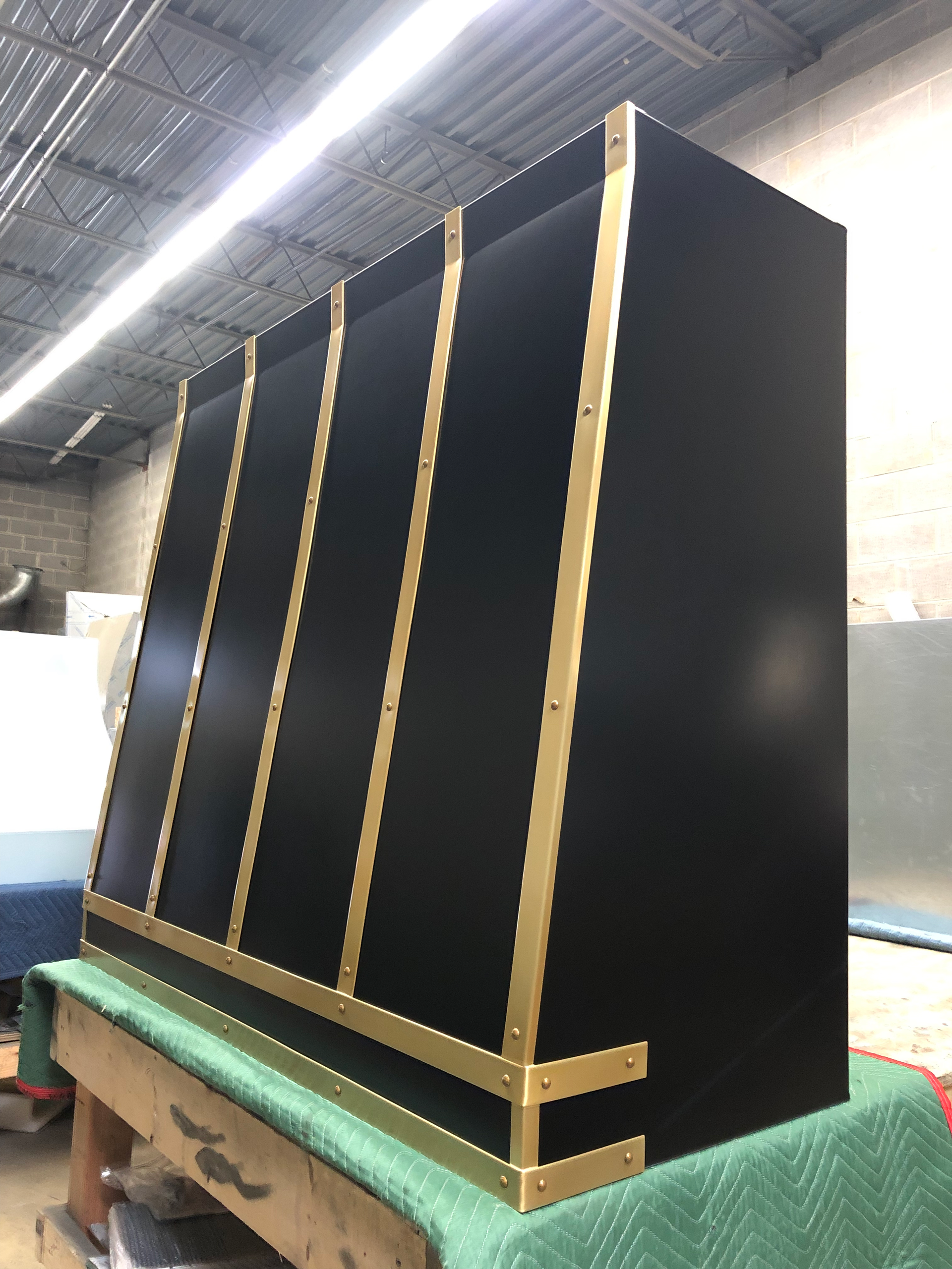 A black cabinet with gold trim is sitting on top of a green table.