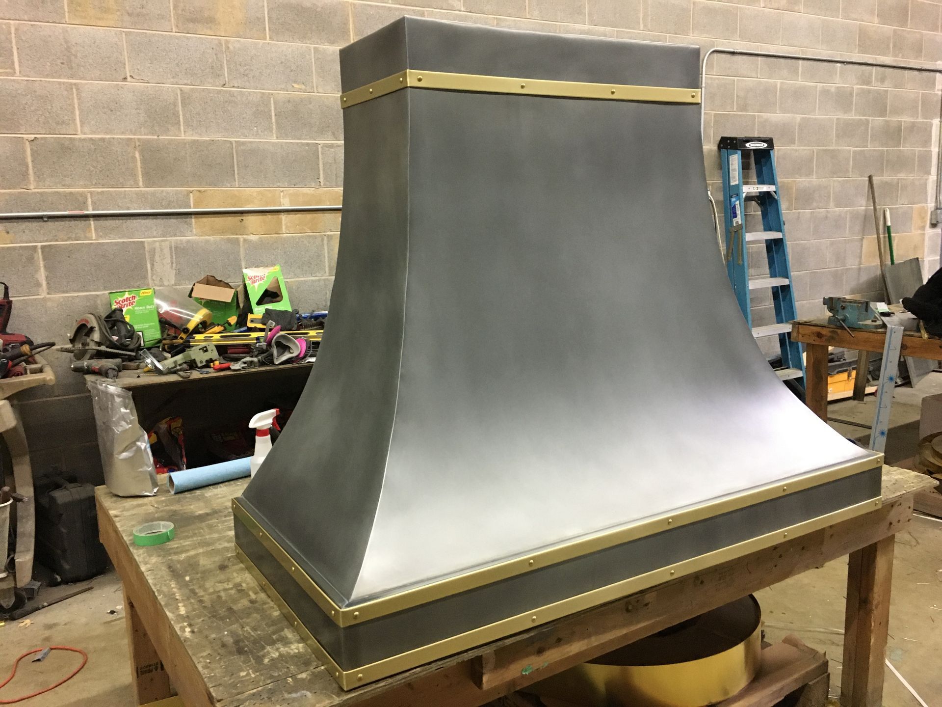 A metal hood is sitting on top of a wooden table.