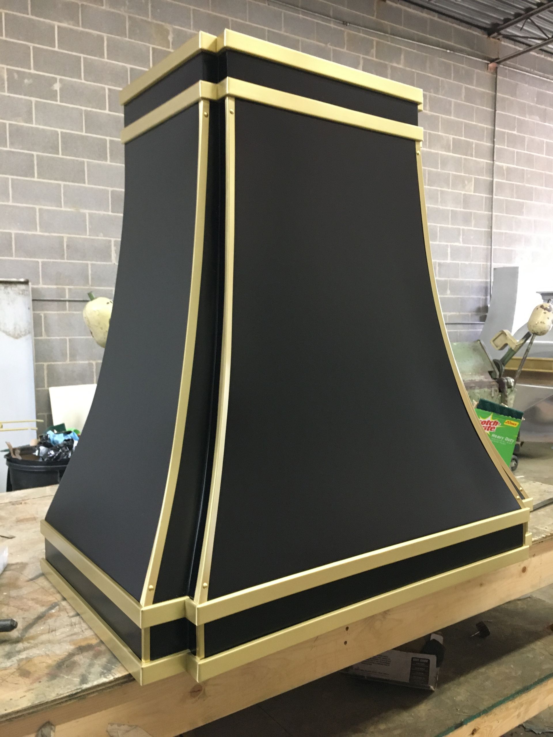 A black and gold hood is sitting on a wooden table