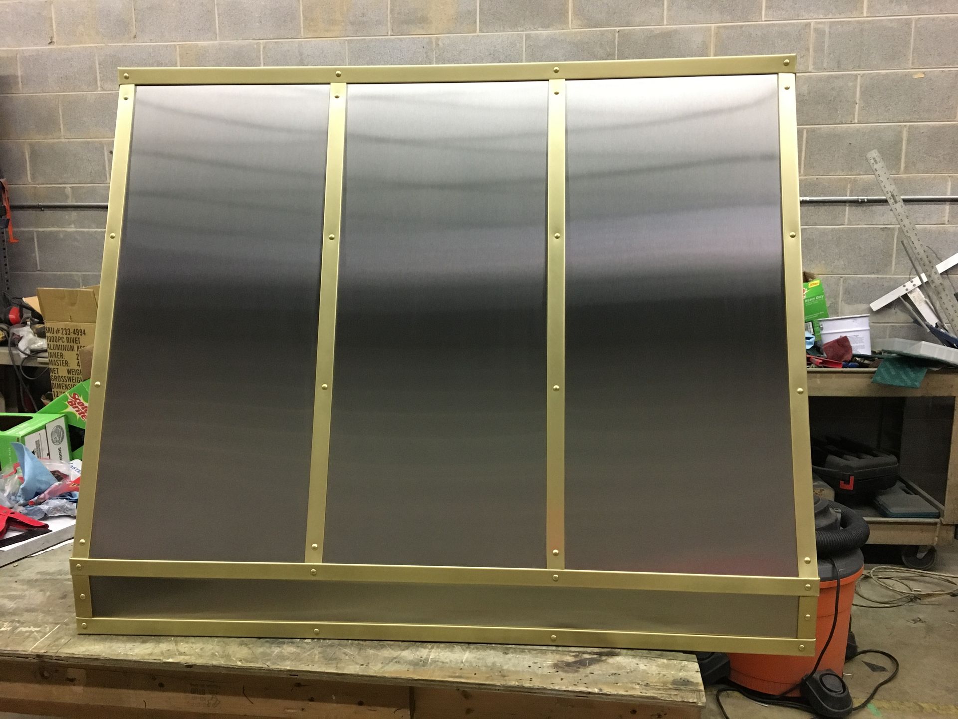 A stainless steel box with brass trim sits on a wooden table
