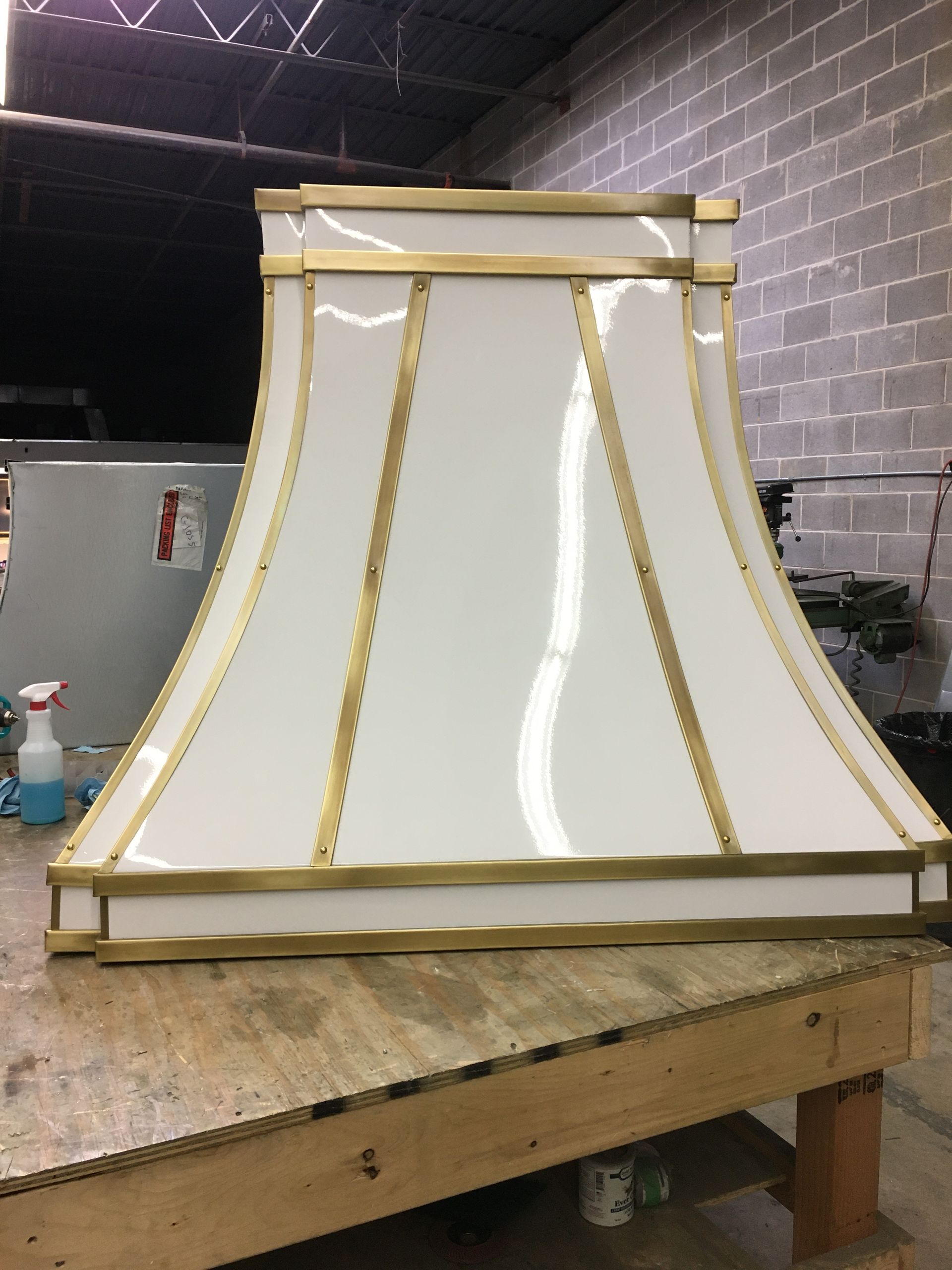 A white lamp shade with gold trim is sitting on a wooden table.