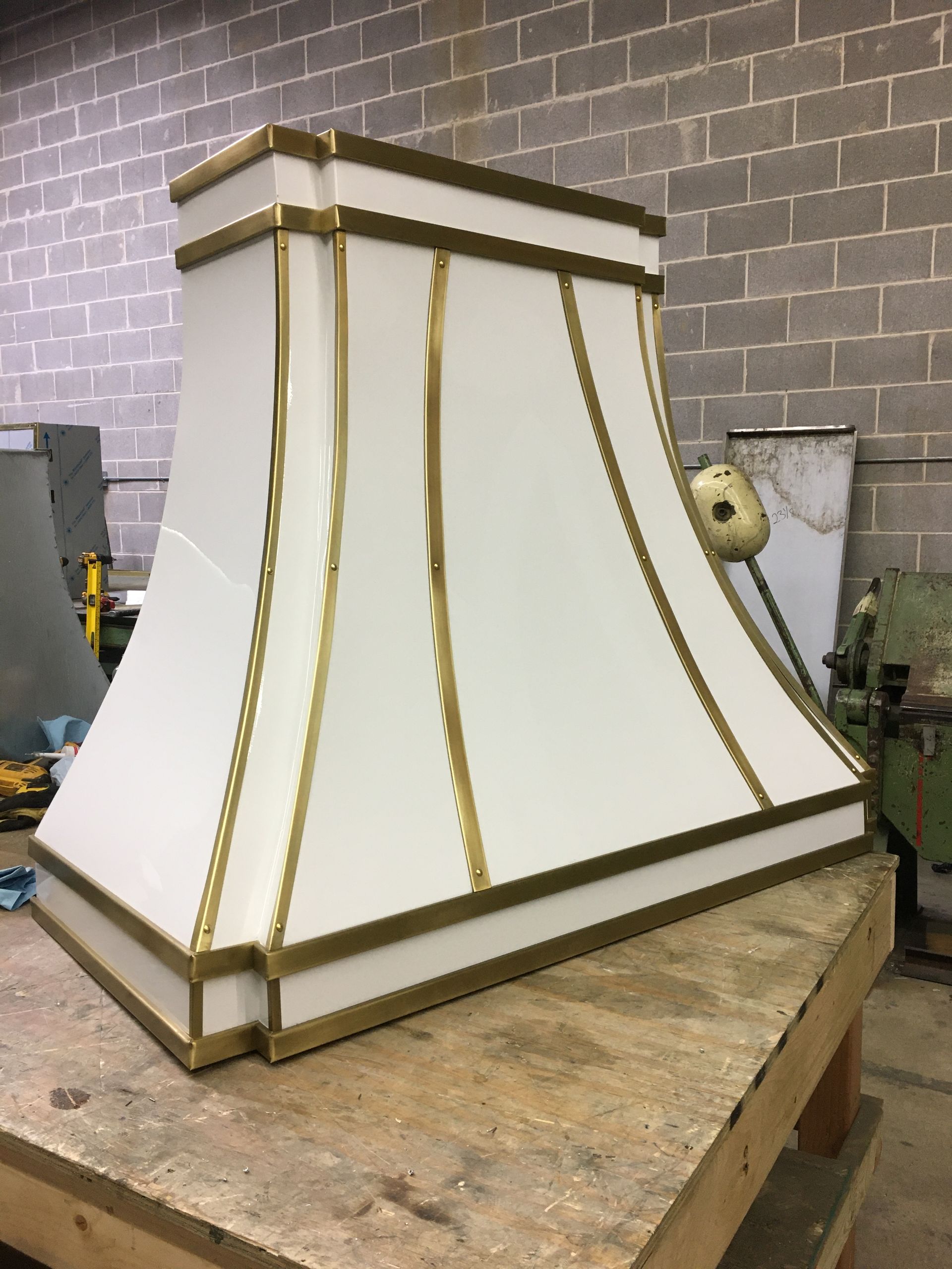 A white lampshade with gold trim is sitting on a wooden table.