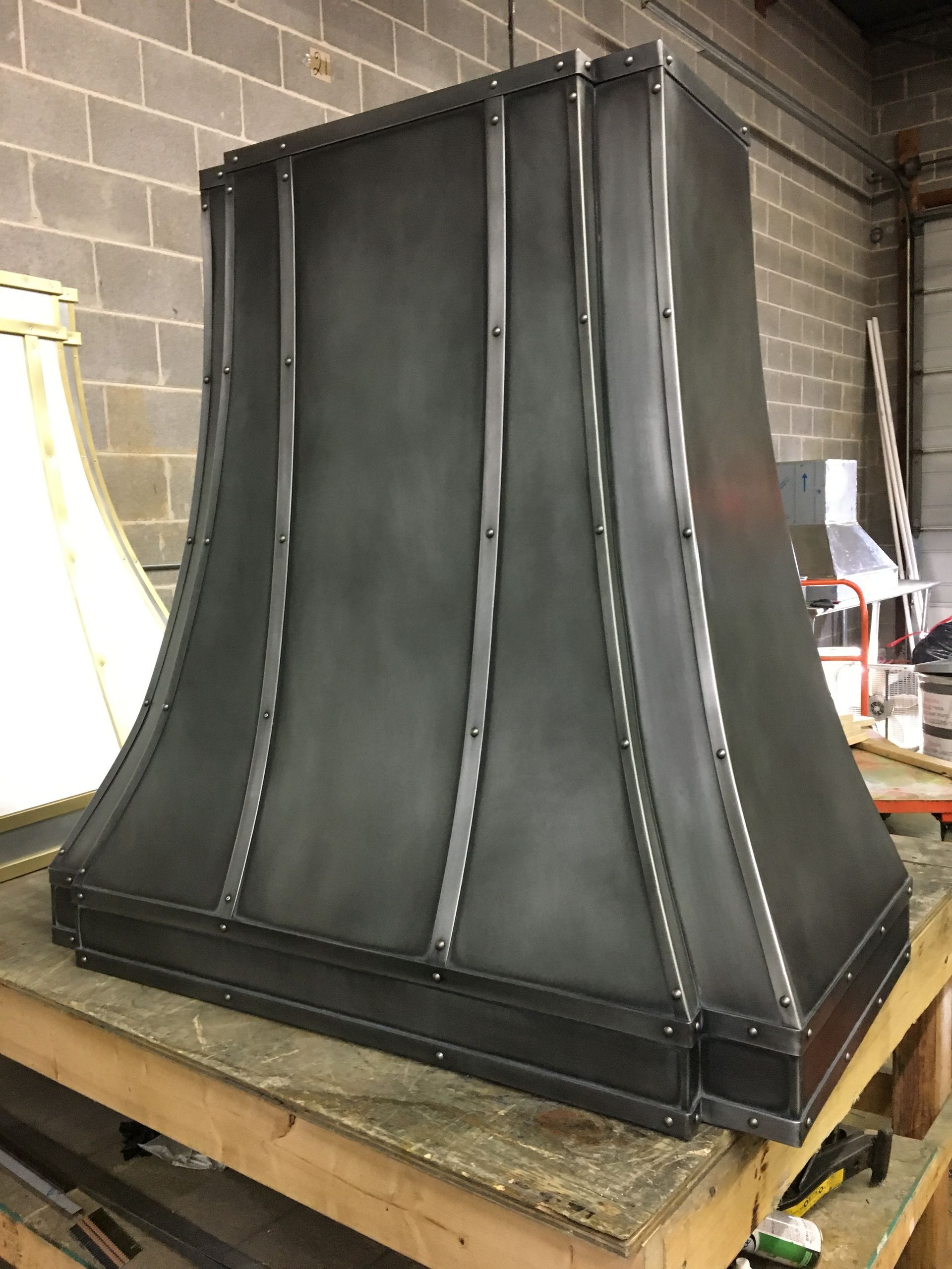 A black metal hood is sitting on top of a wooden table.