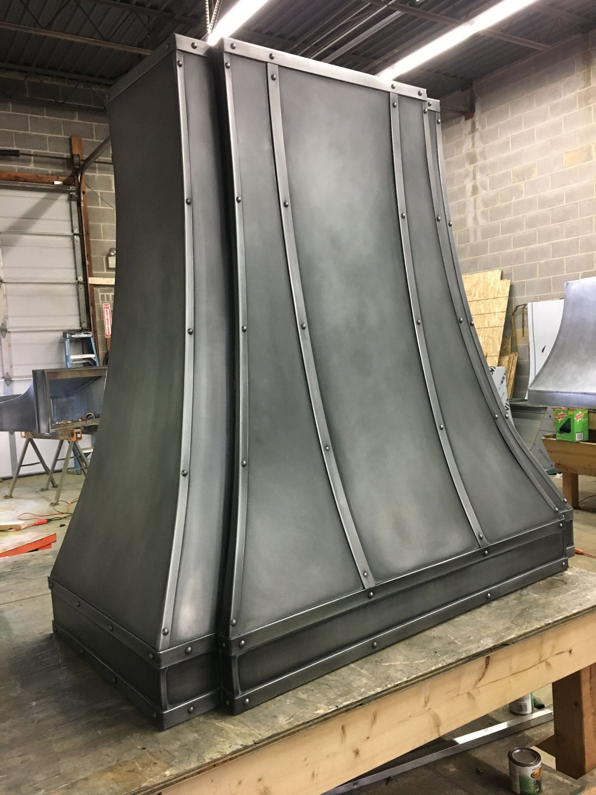 A large metal hood is sitting on top of a wooden table.