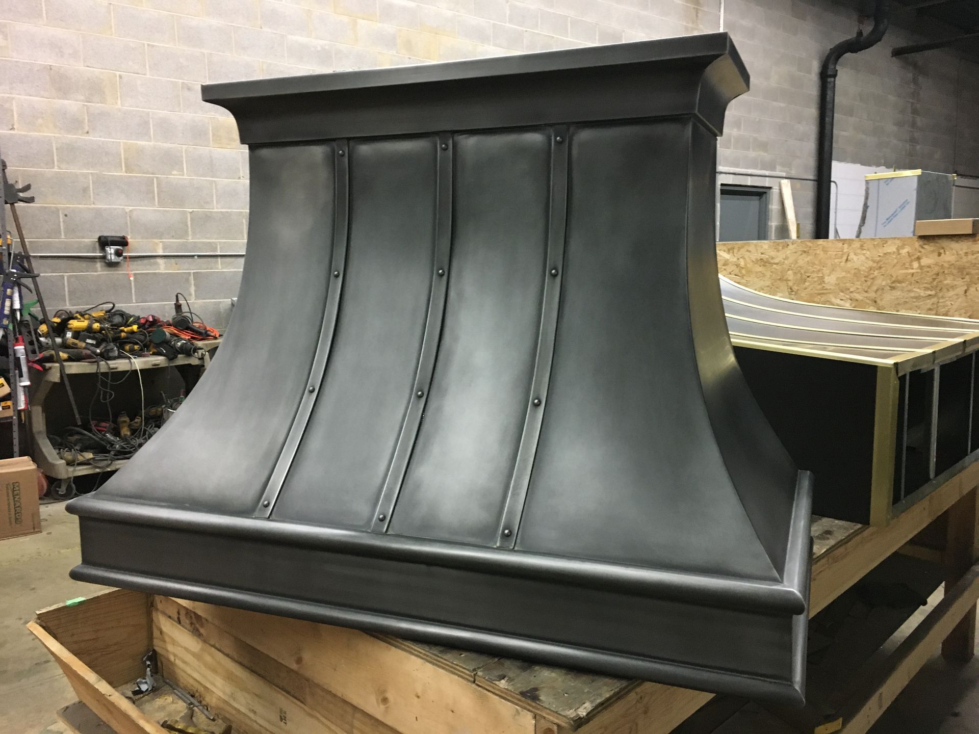 A black metal hood is sitting on top of a wooden table.