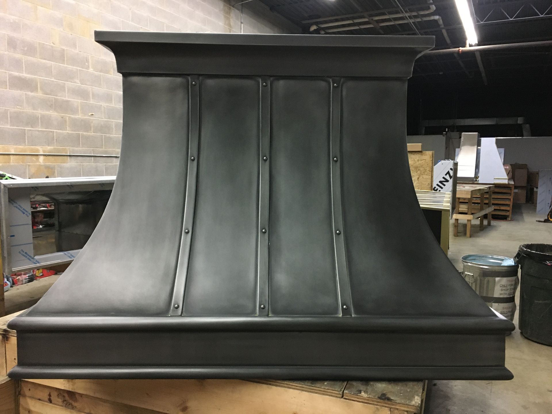 A black hood is sitting on top of a wooden table in a warehouse.