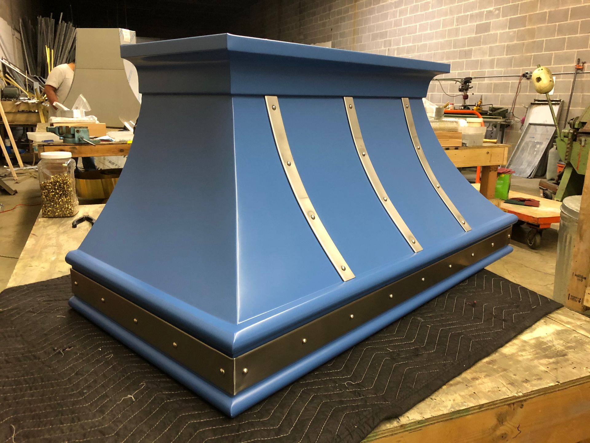 A blue hood is sitting on a black mat in a room.