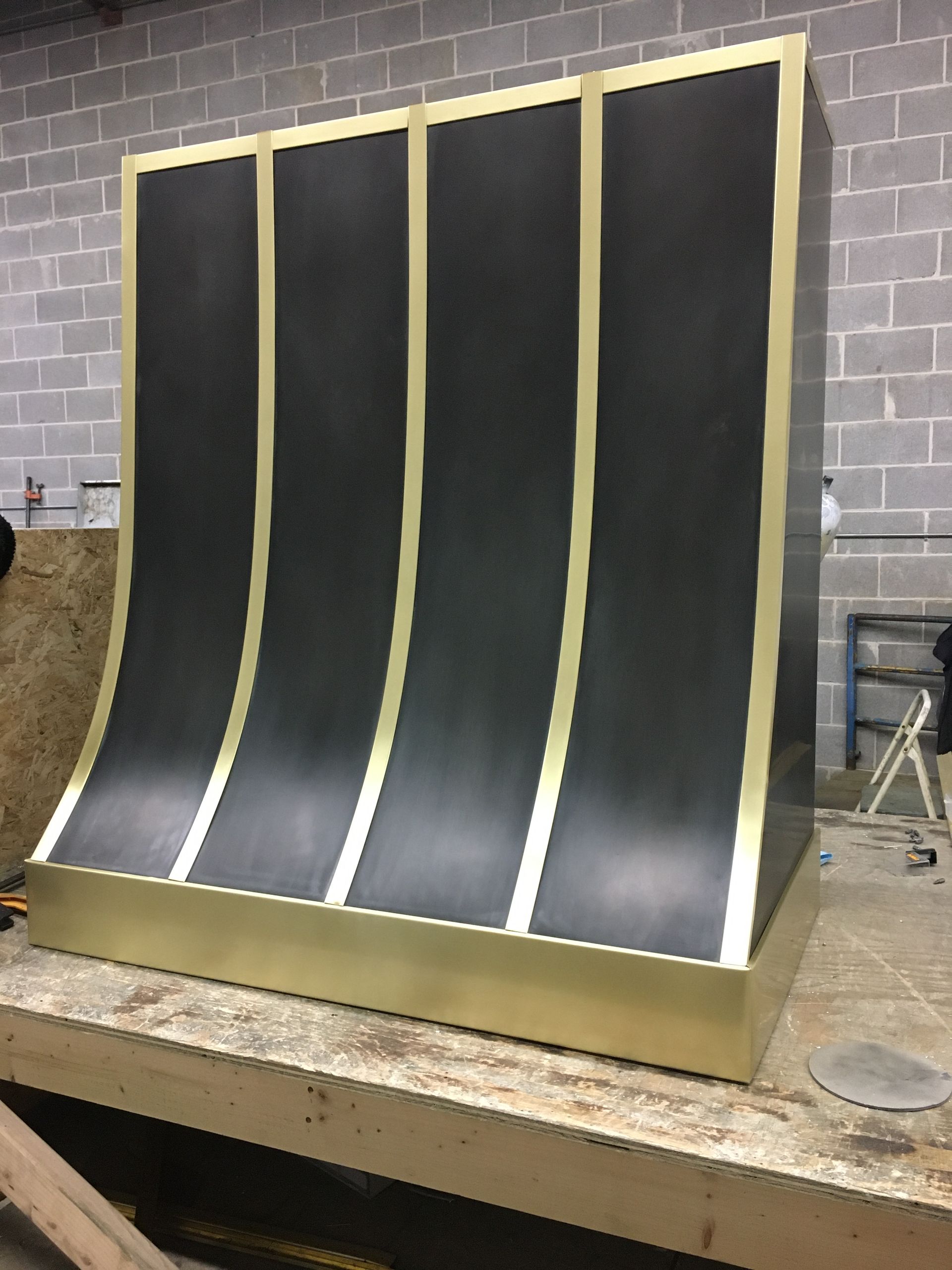 A black and gold item is sitting on a wooden table in front of a brick wall.