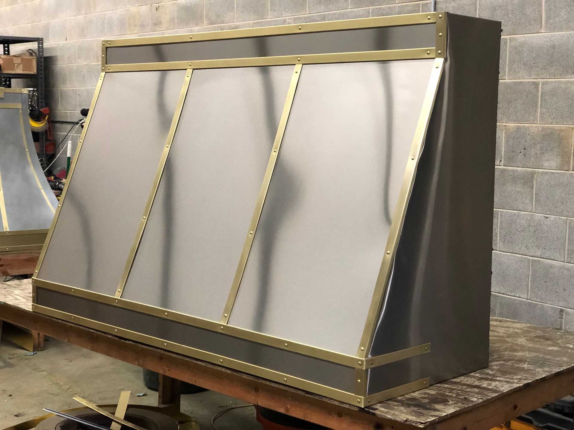 A stainless steel hood is sitting on top of a wooden table.