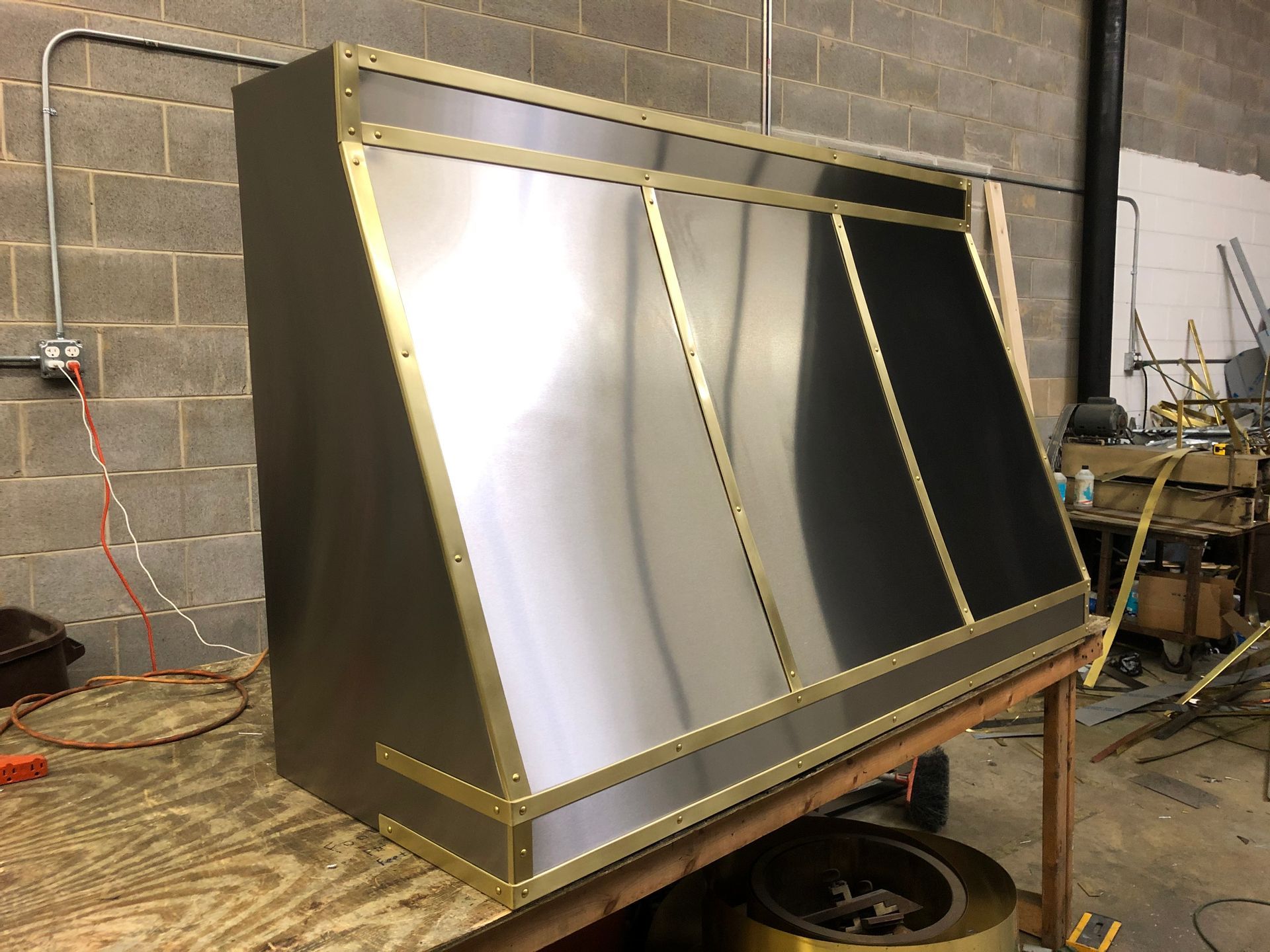 A stainless steel hood is sitting on top of a wooden table.