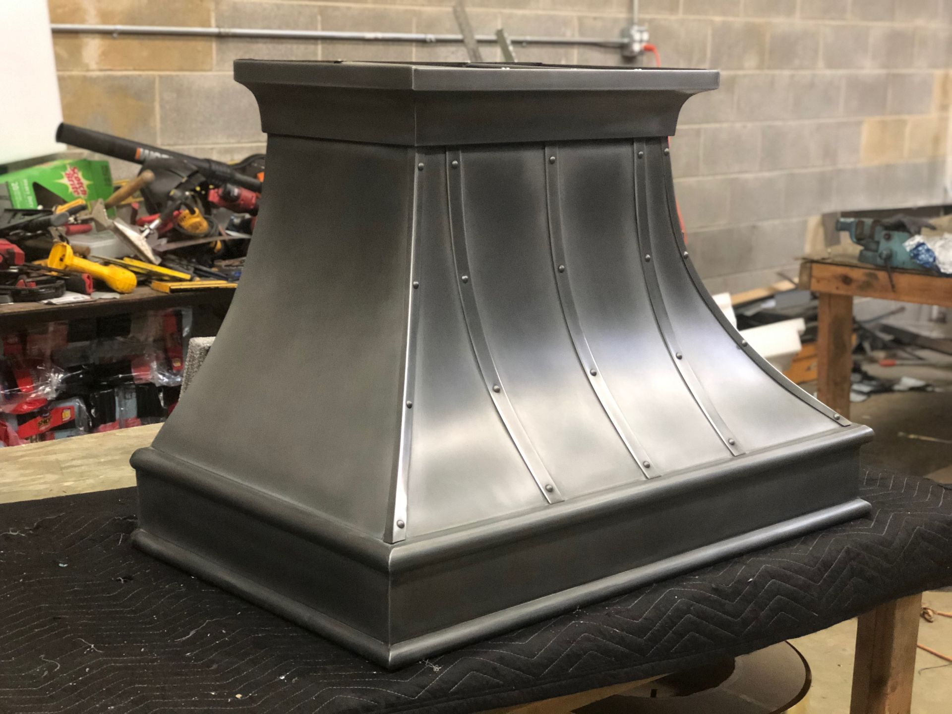 A stainless steel hood is sitting on a table in a workshop.