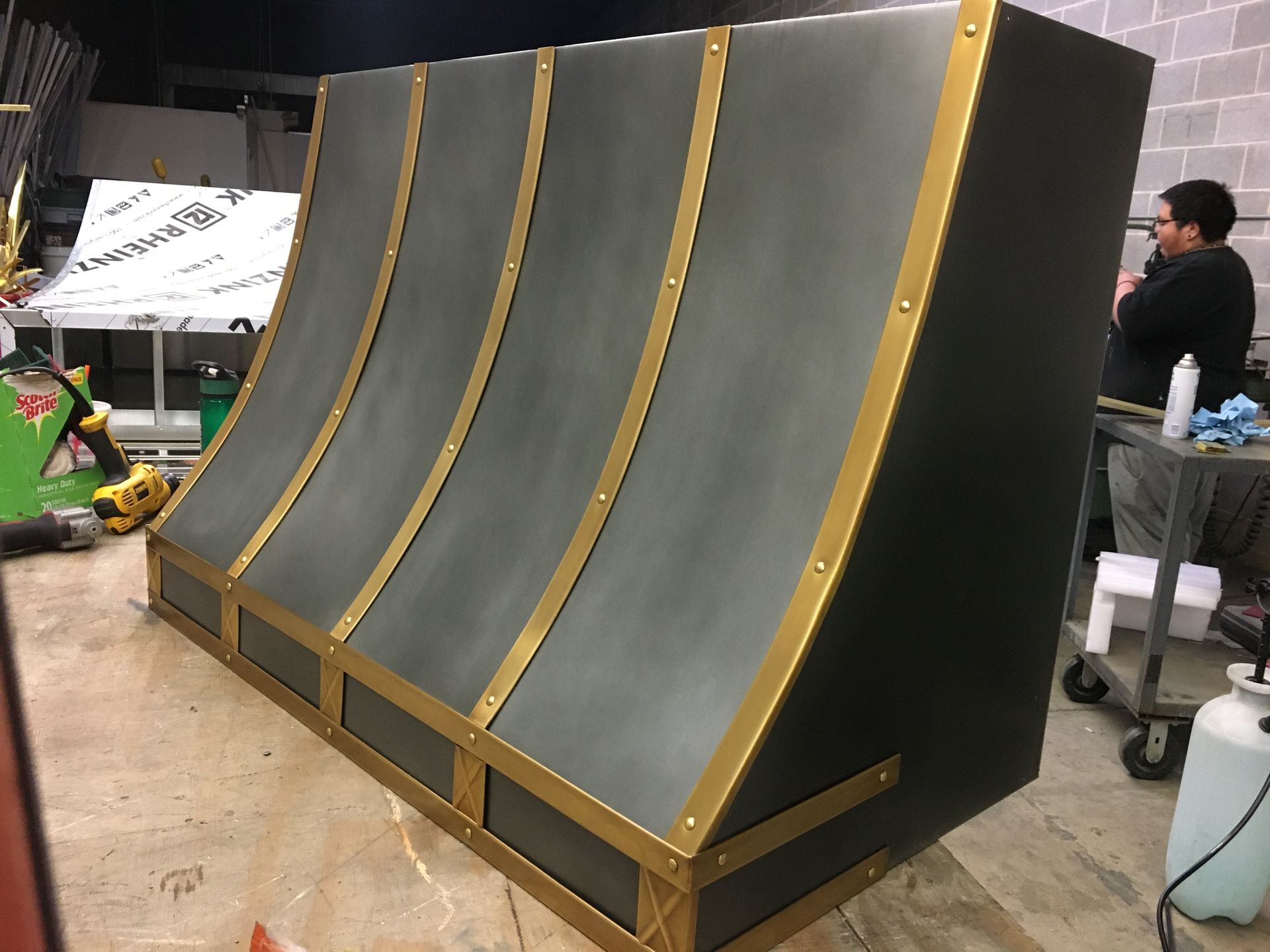 A man is standing next to a large gray and gold object.