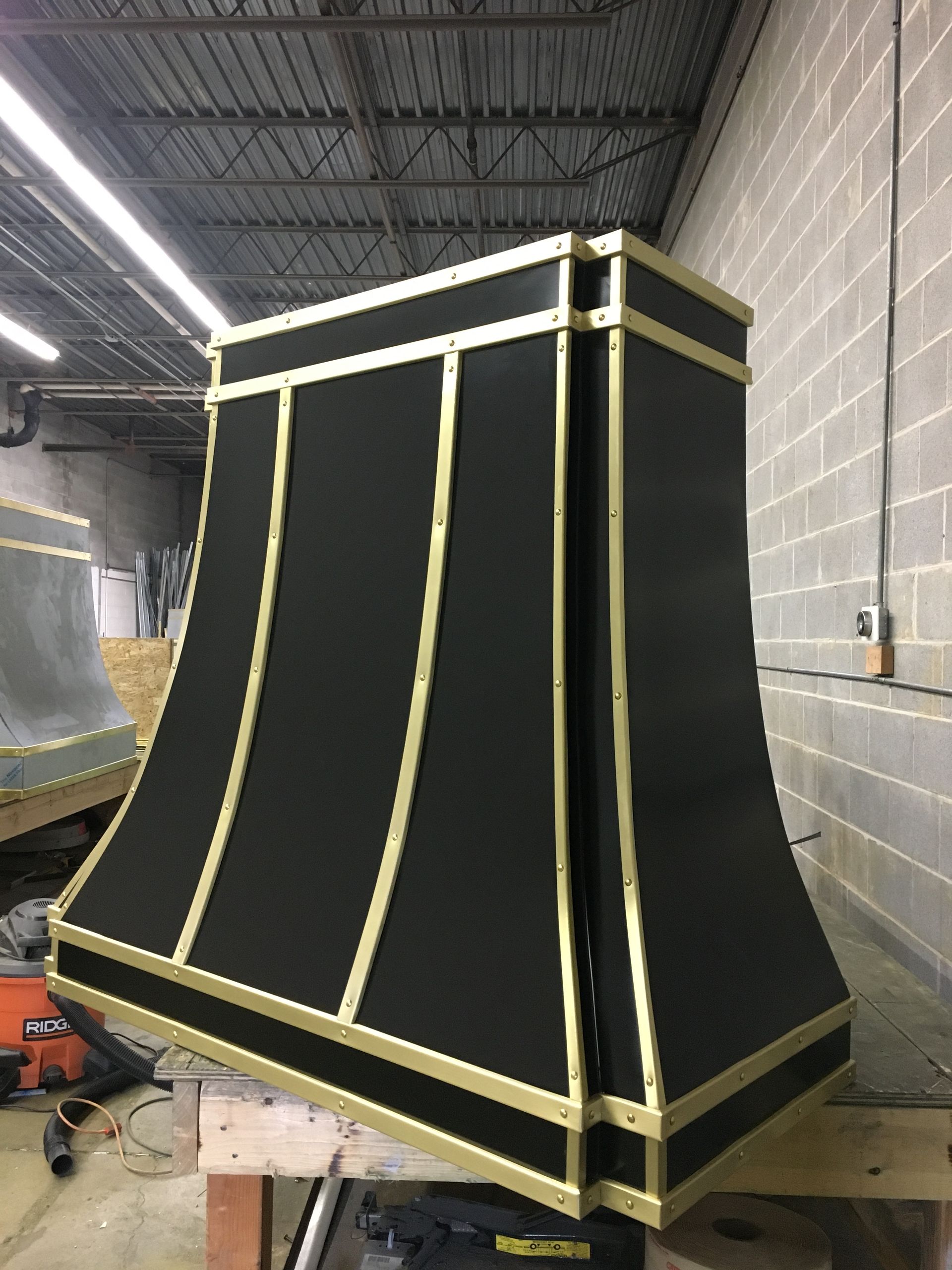 A black and gold hood is sitting on a wooden table.