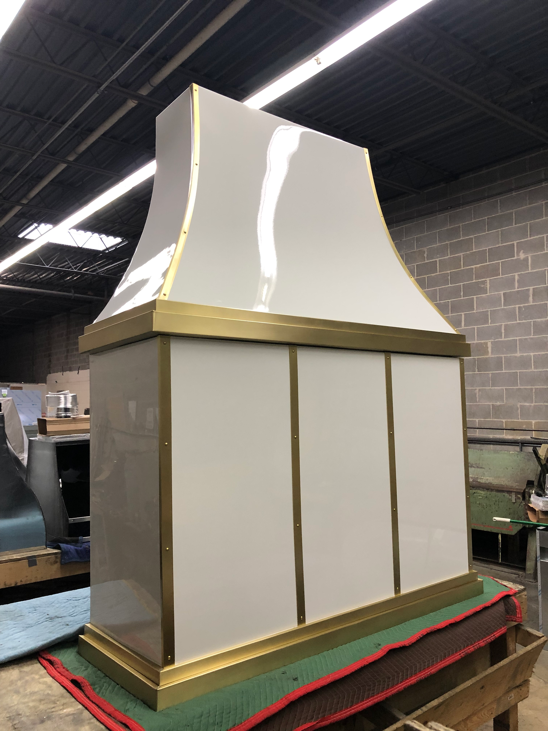 A white and gold hood is sitting on a wooden table in a room.