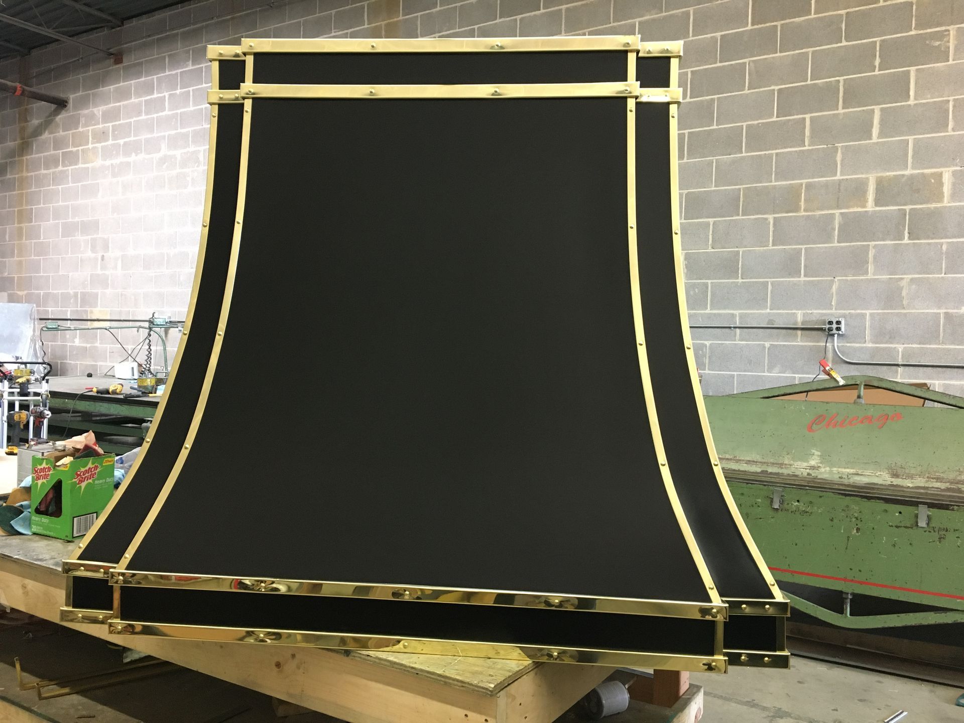 A black and gold lampshade is sitting on top of a wooden table.