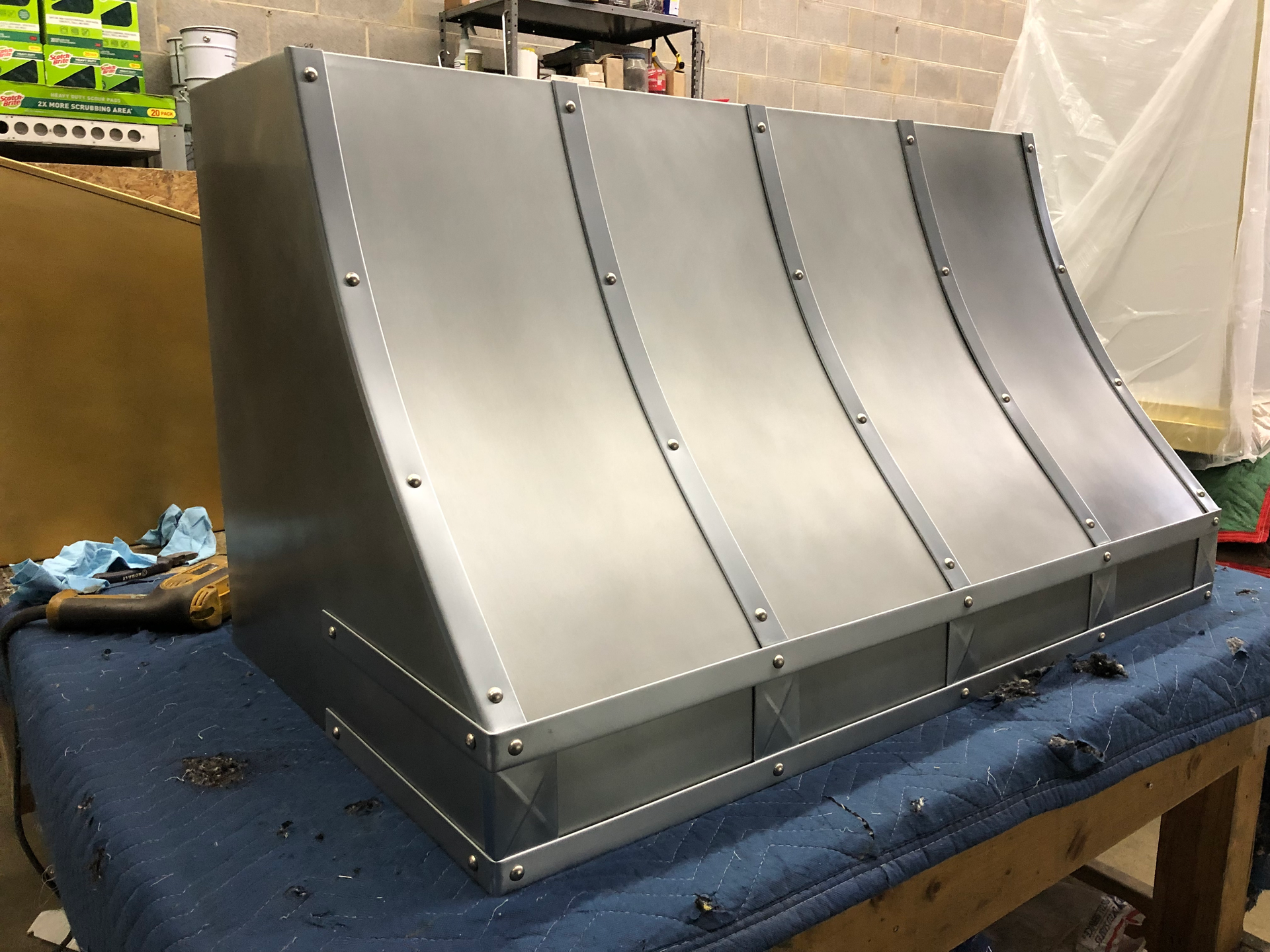 A stainless steel hood is sitting on top of a wooden table.