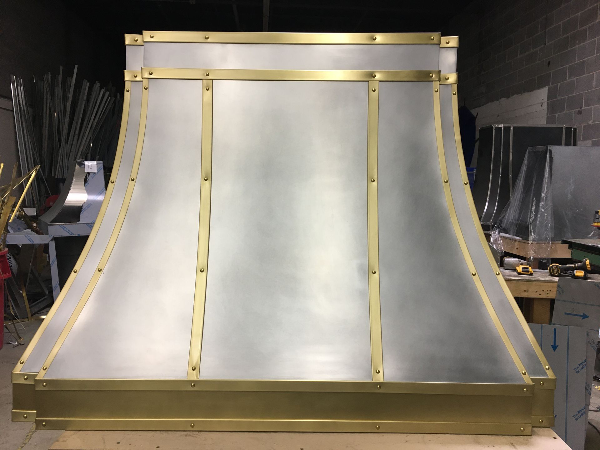 A stainless steel hood with brass trim sits on a wooden table