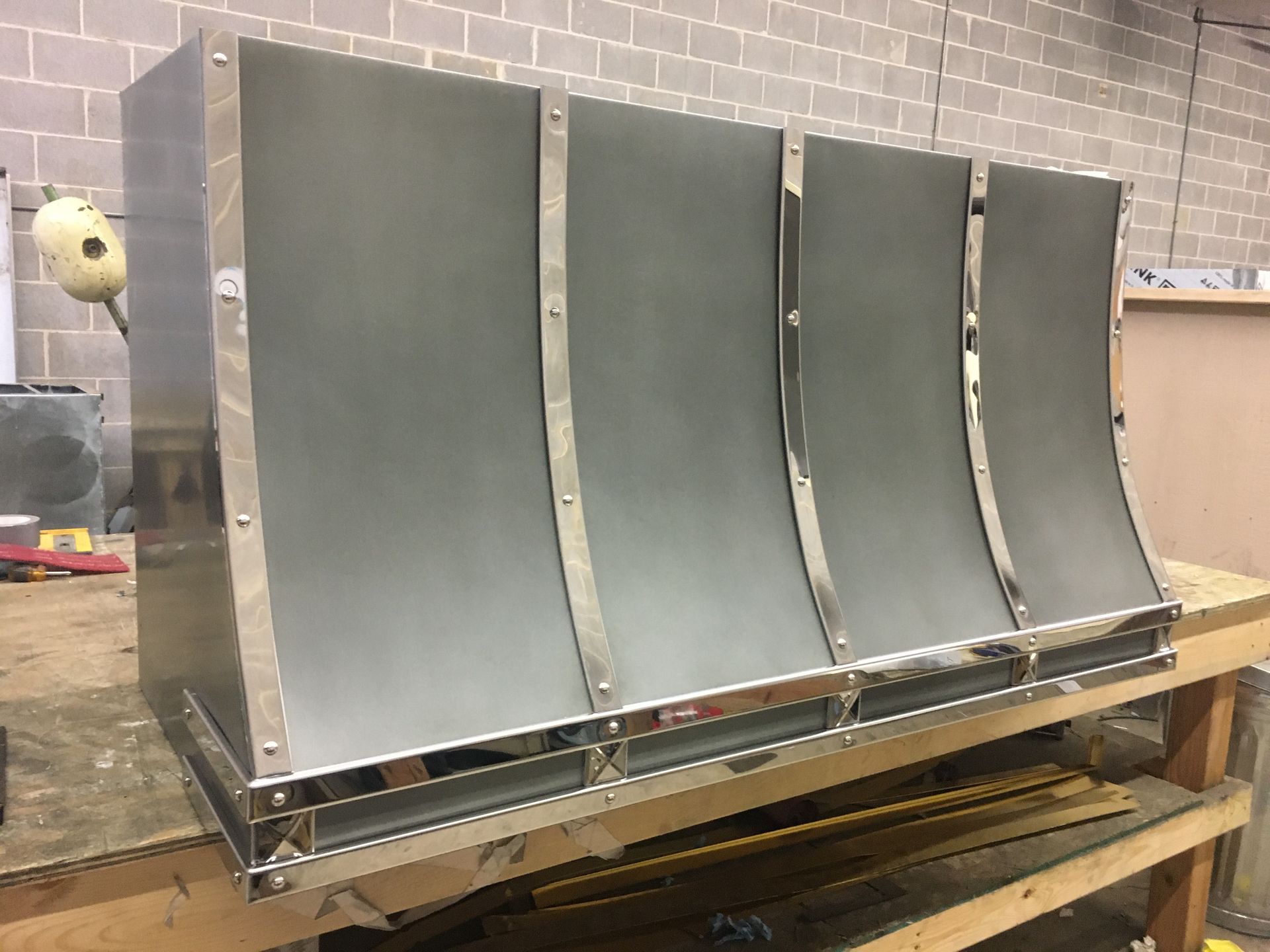 A stainless steel hood is sitting on top of a wooden table.