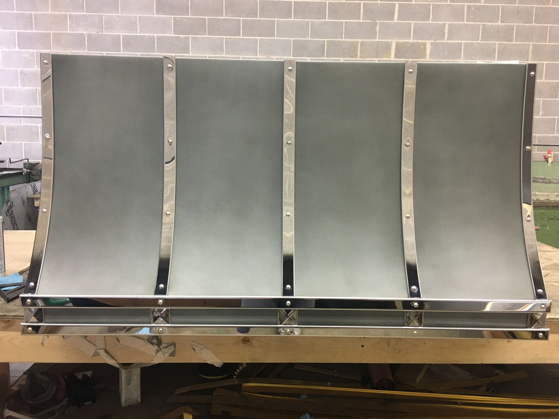 A large metal object is sitting on top of a wooden table in front of a brick wall.