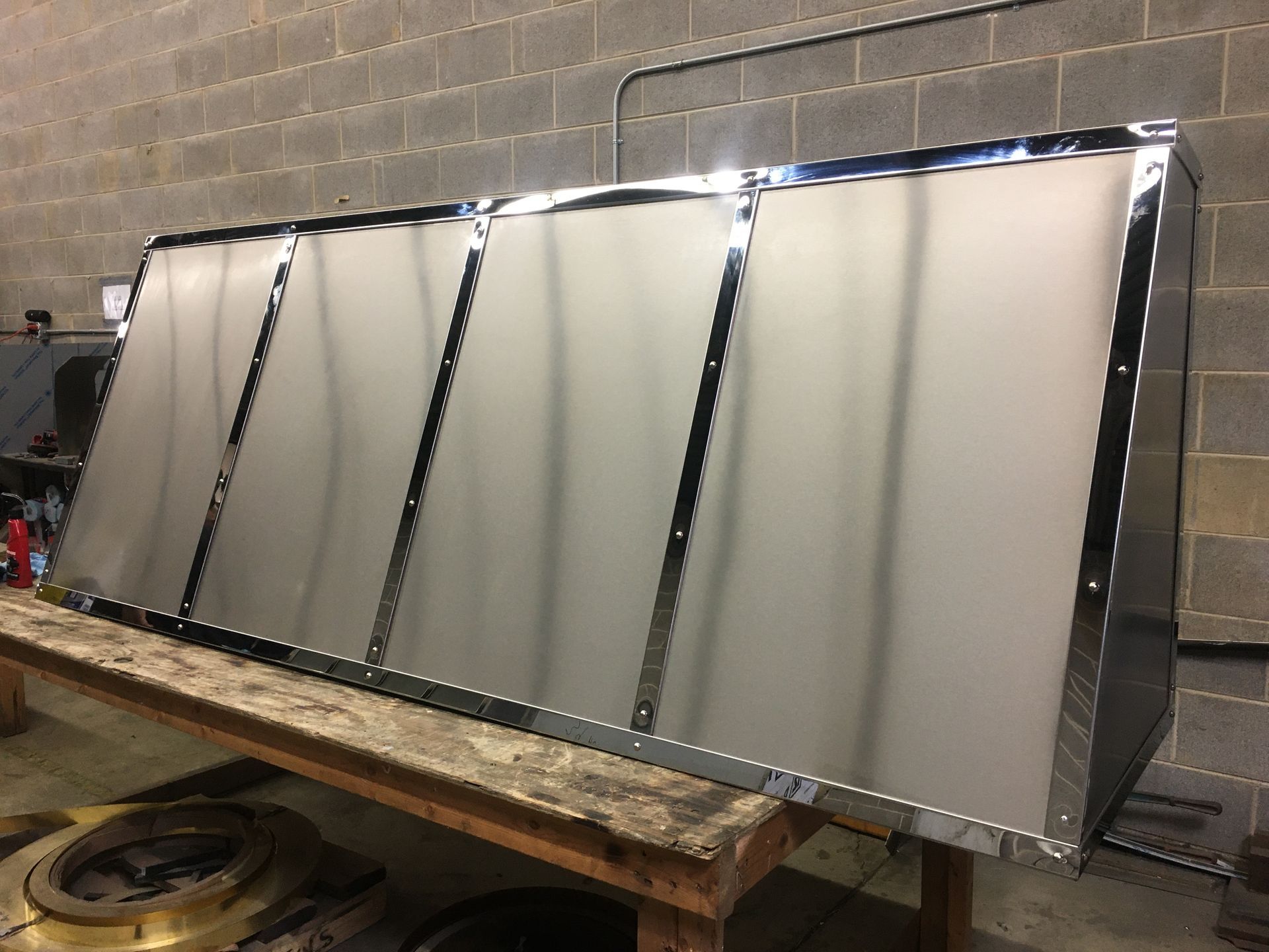 A stainless steel hood is sitting on top of a wooden table.