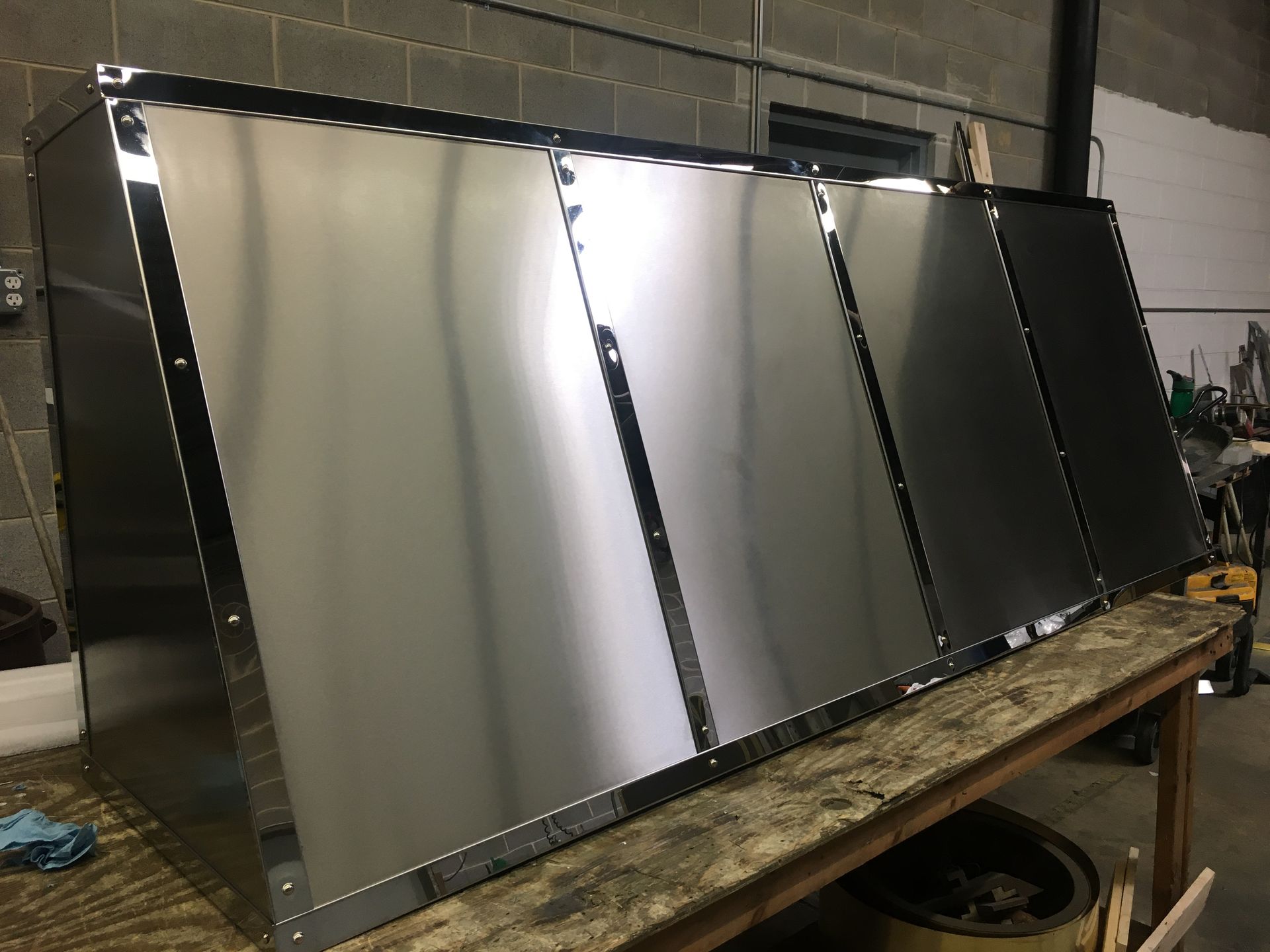 A stainless steel cabinet is sitting on top of a wooden table.