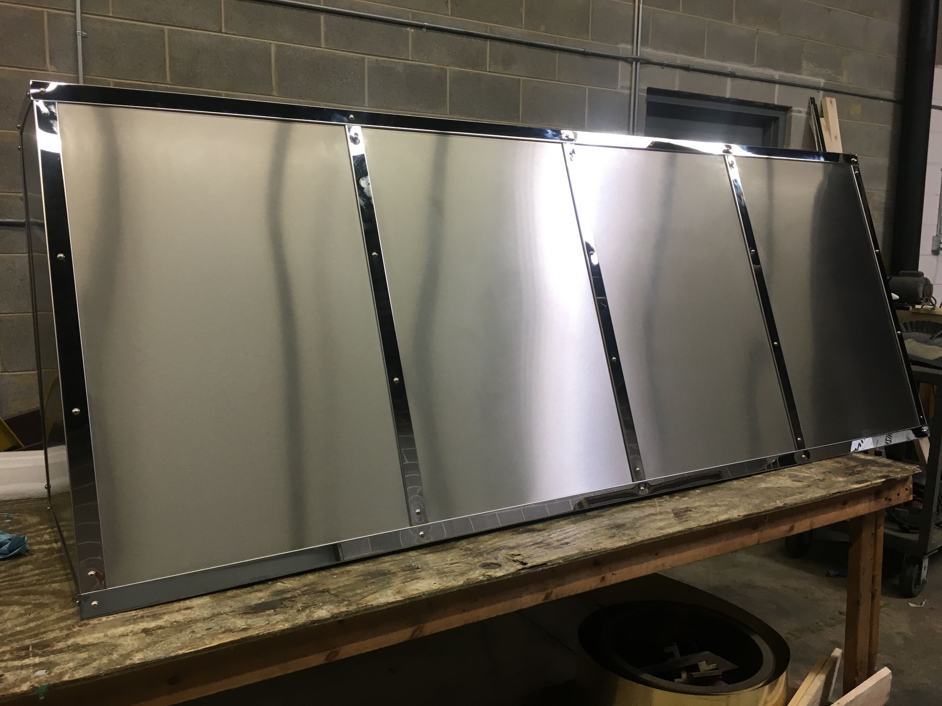 A large piece of stainless steel is sitting on top of a wooden table.